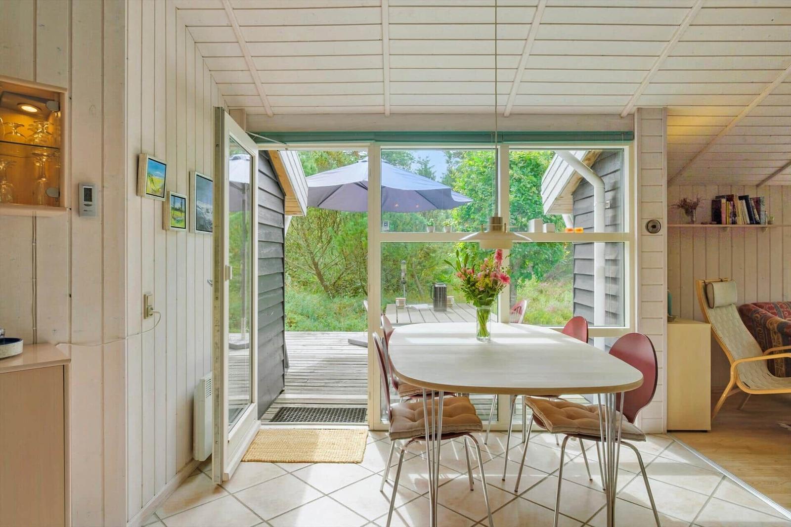 Essbereich mit ovalem Holztisch, Blumen, Pendelleuchte und Blick zur Terrasse.
