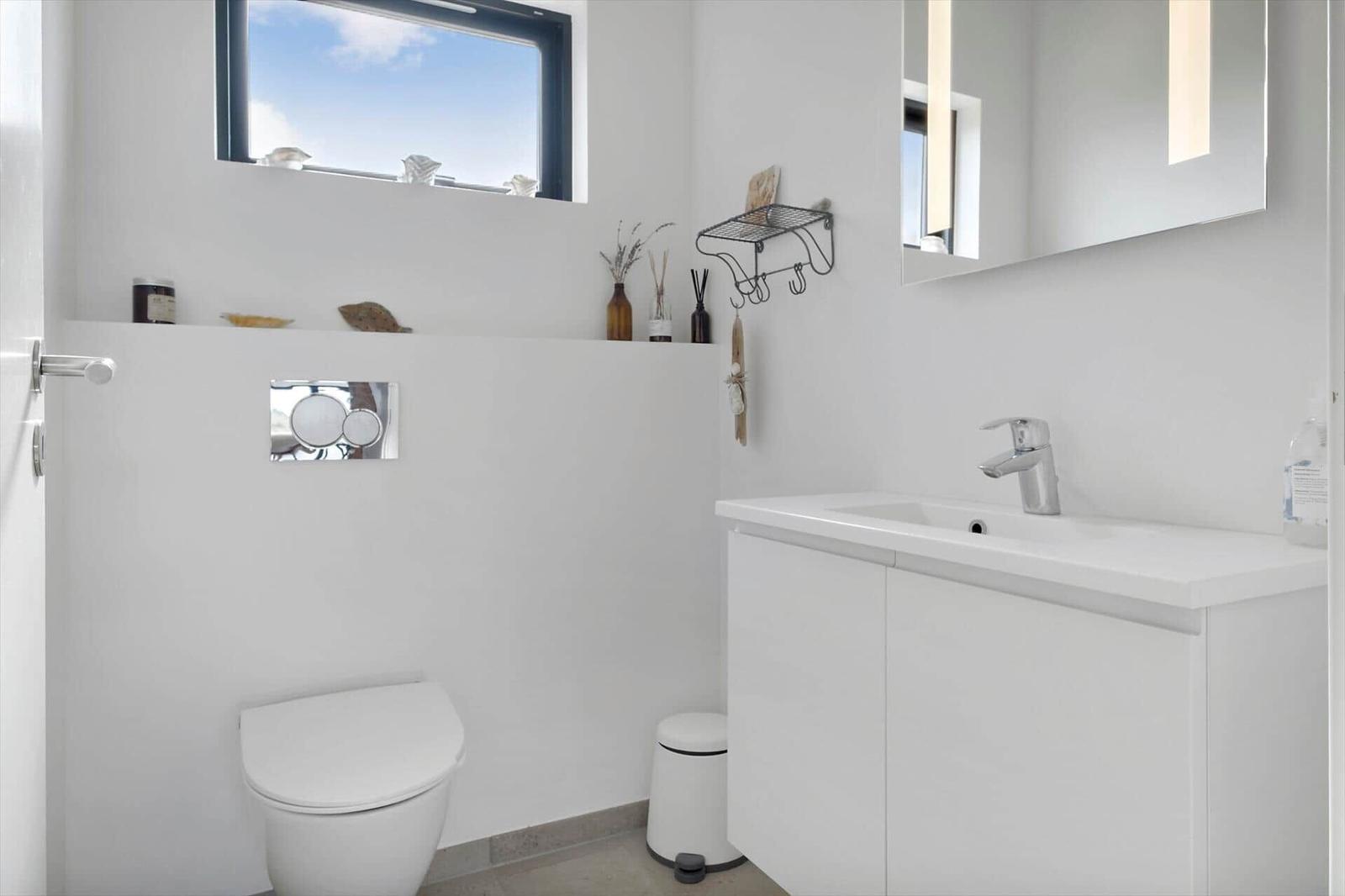 Helles Bad mit wandhängendem WC, Waschtisch und Spiegel.