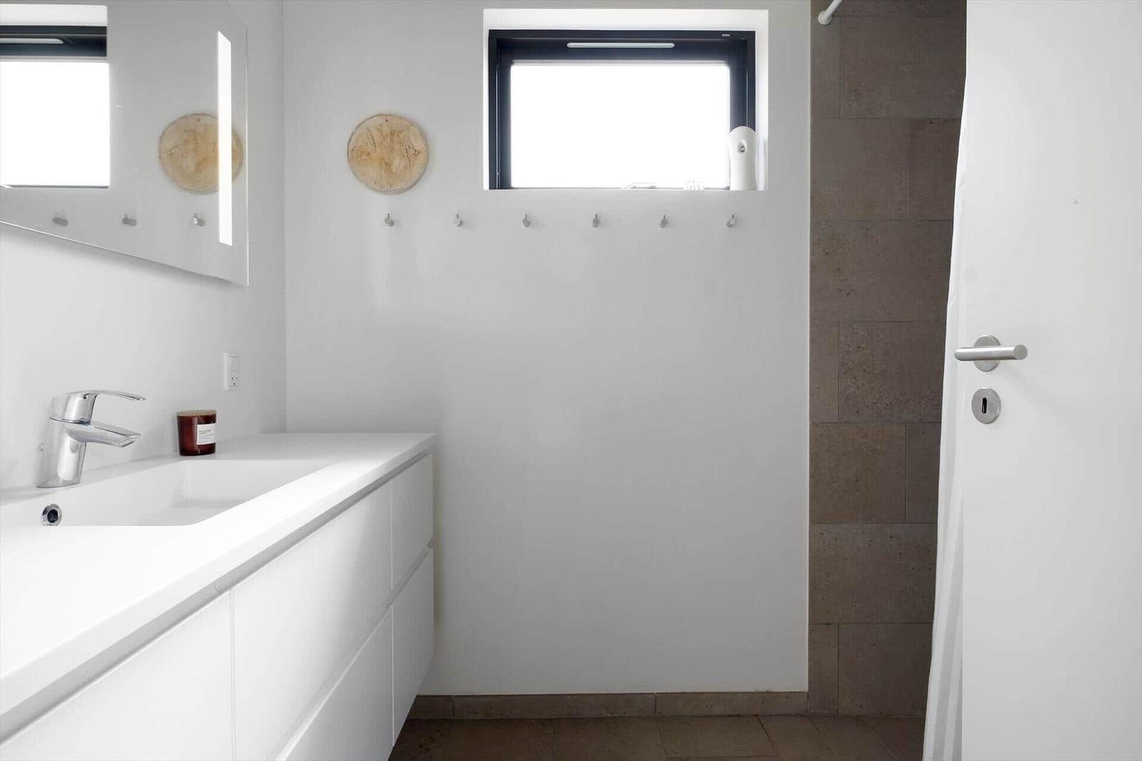 Badezimmer mit Waschtisch, beleuchtetem Spiegel und Duschbereich.