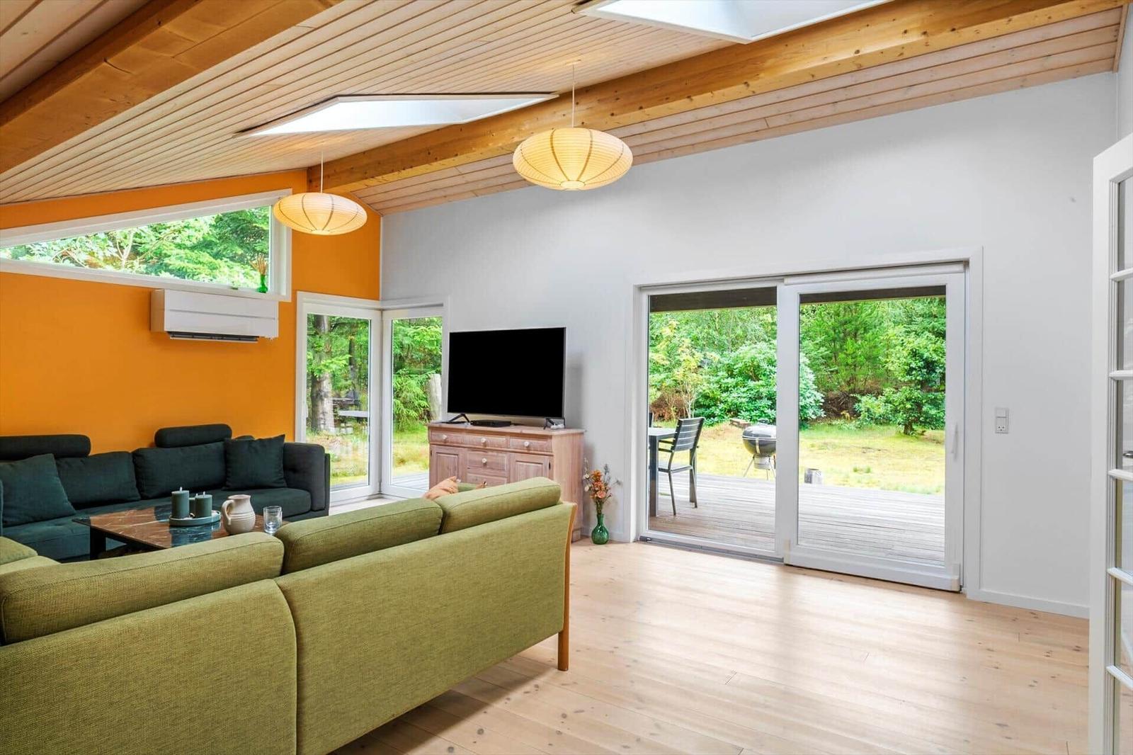 Living room with sofas, orange wall and terrace door with a grill outside.