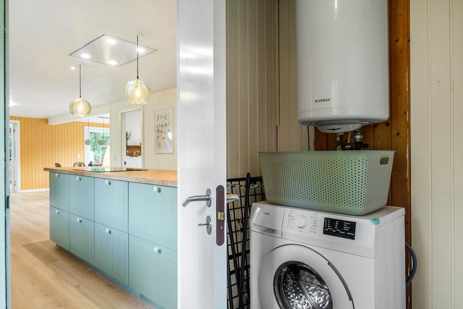 Laundry room with washing machine and view of the green kitchen island.