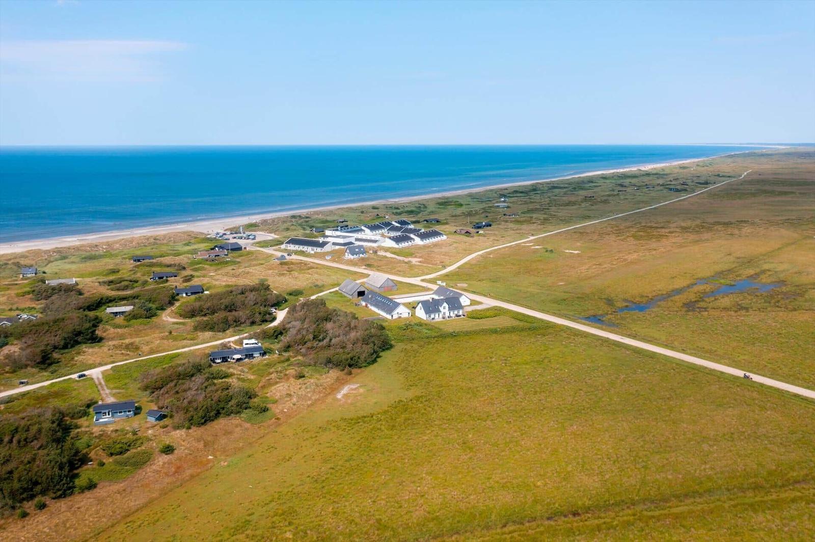 Aerial view of the coast with holiday homes, grassland and the sea.