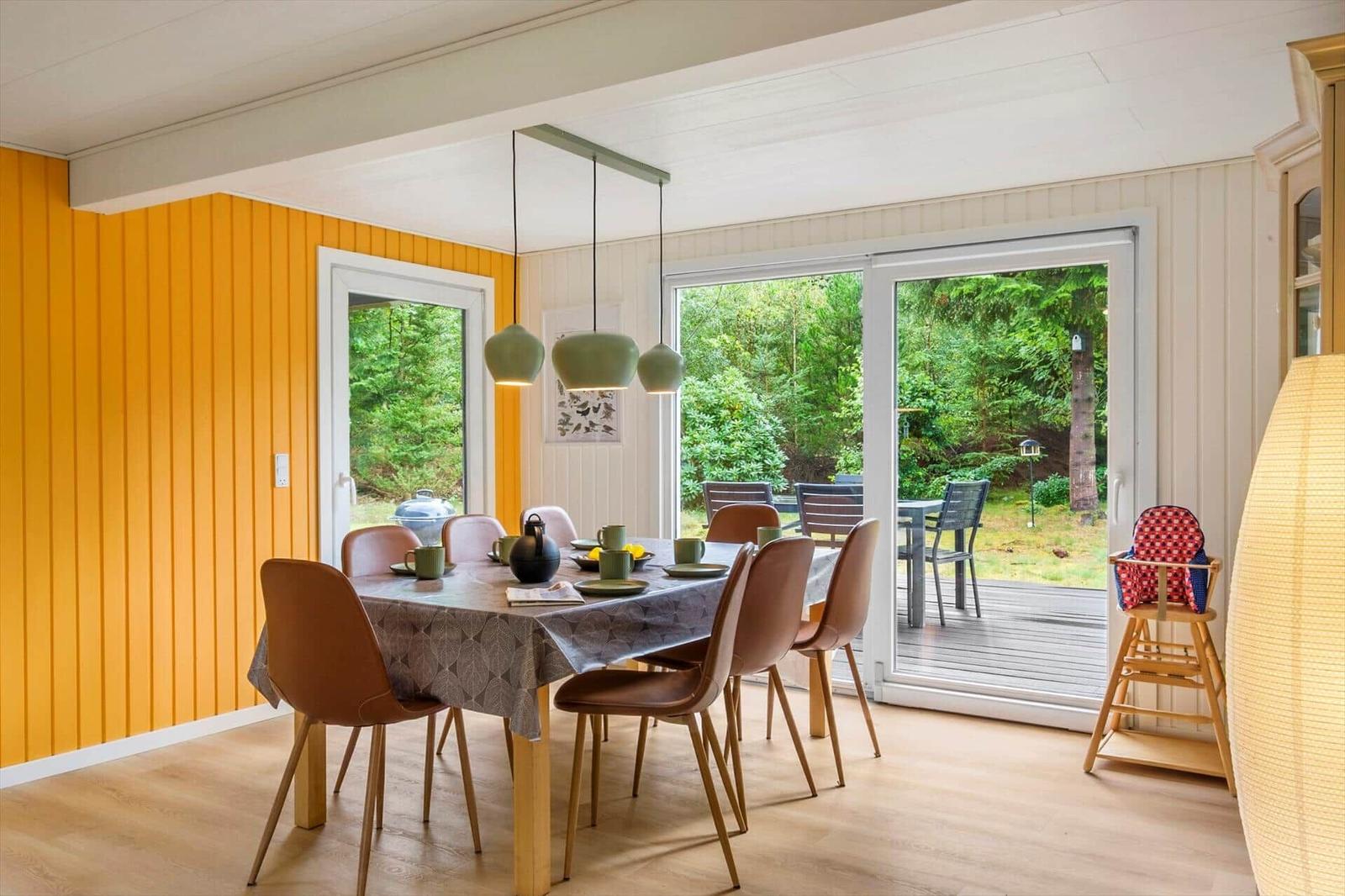 Dining area with set wooden table, brown chairs and terrace glass door.