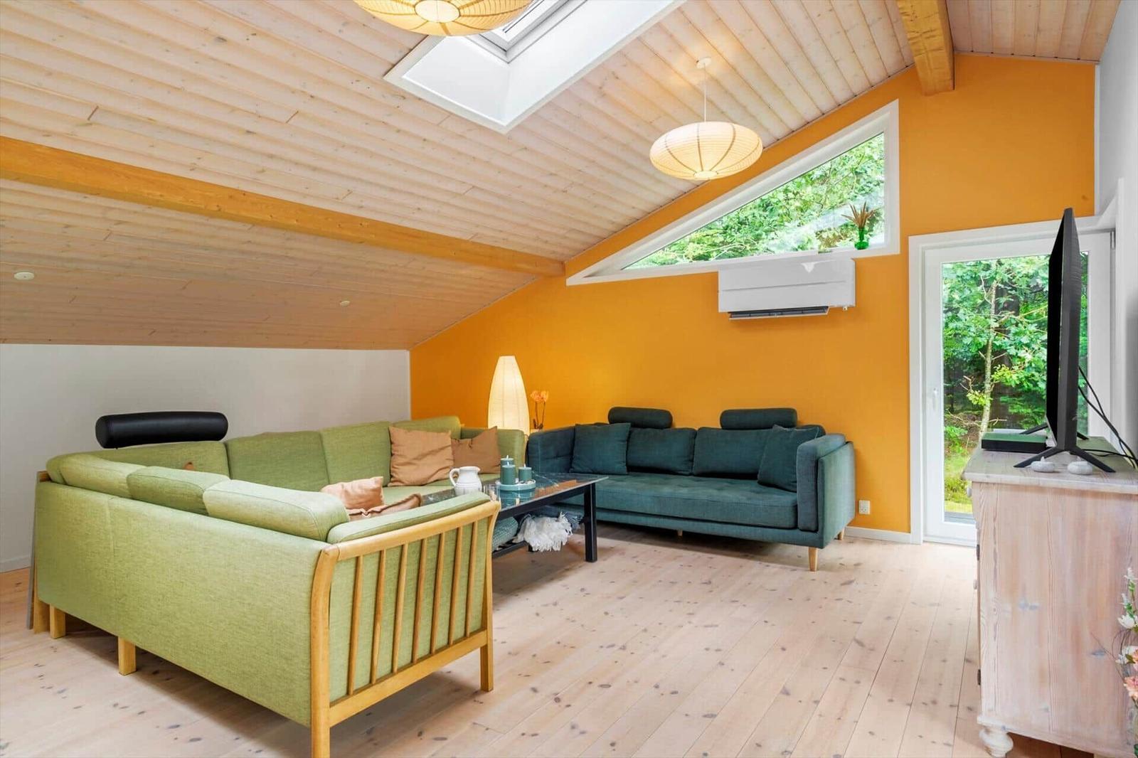 Living room with green corner sofa, teal sofa and orange accent wall.