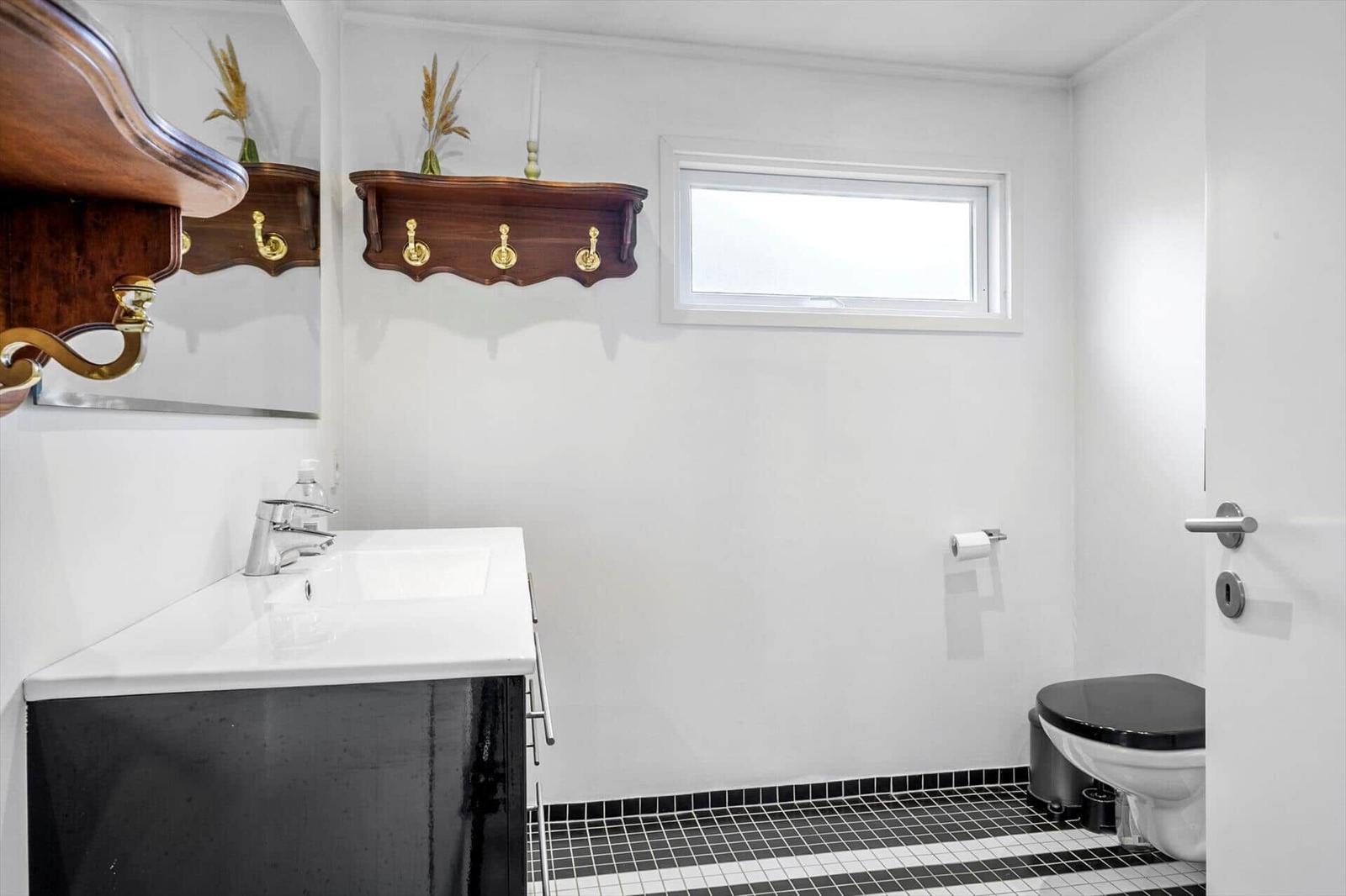 Bathroom with white sink, dark vanity cabinet and toilet with black lid.