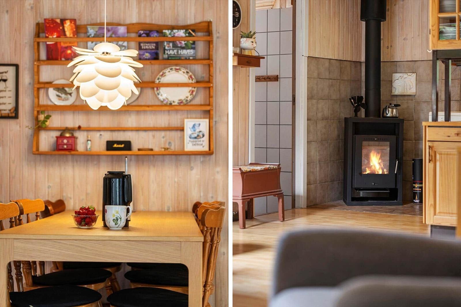 Wooden dining table with pinecone lamp and wood stove with fire in a paneled living room.