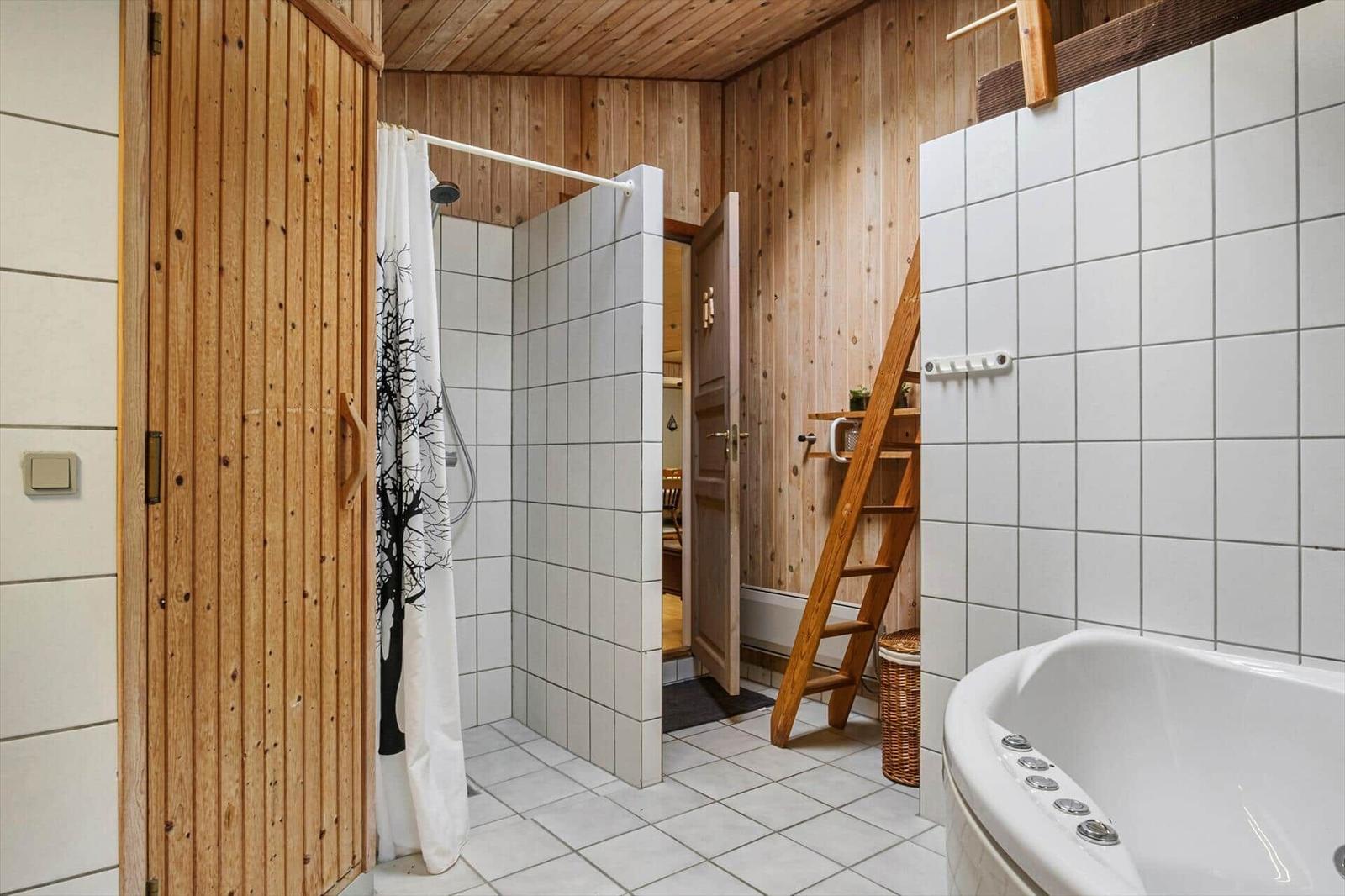 Bathroom with shower behind tree curtain, whirlpool tub, wooden door and wicker basket.