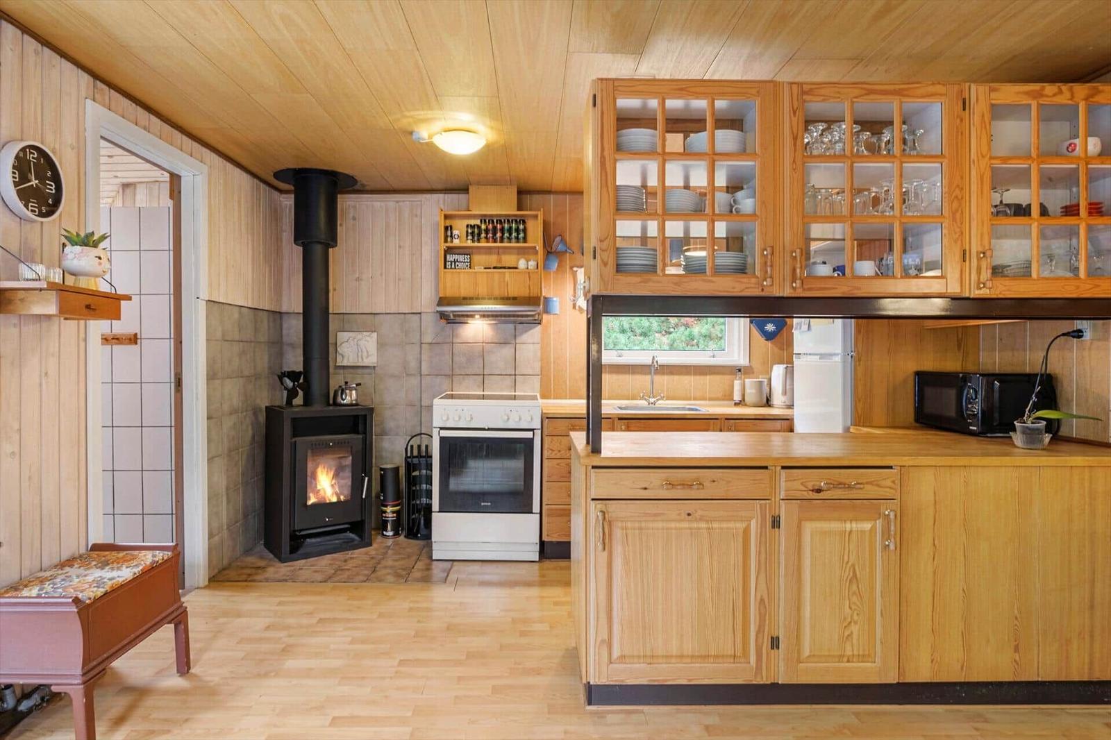 Wooden kitchen with wood stove, white cooker, glass cabinets, microwave and white fridge.