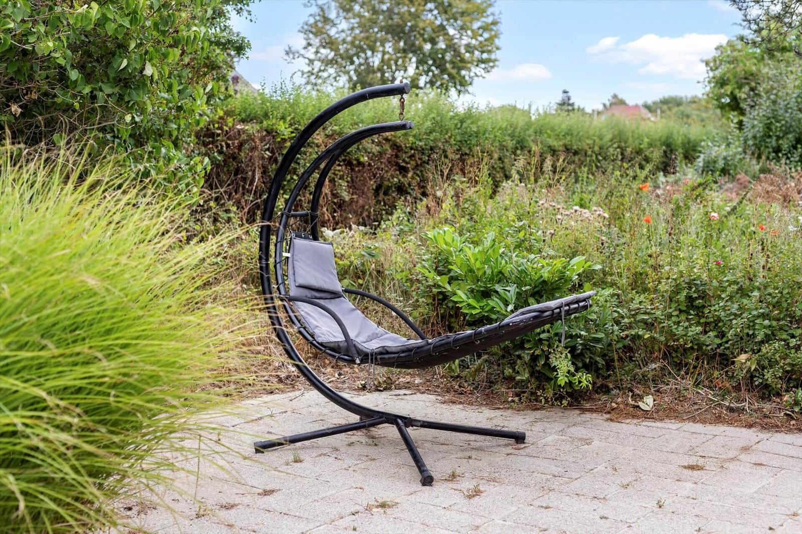 Hanging lounger with grey cushion on a stone patio in the garden.