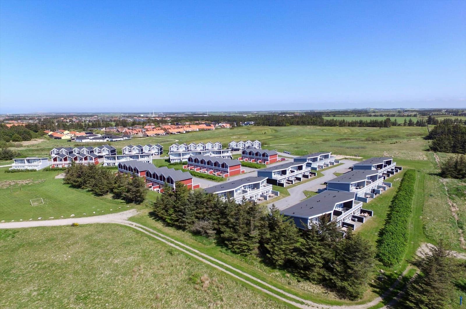Luftbild von Reihenhäusern mit grauen und roten Fassaden zwischen Feldern.
