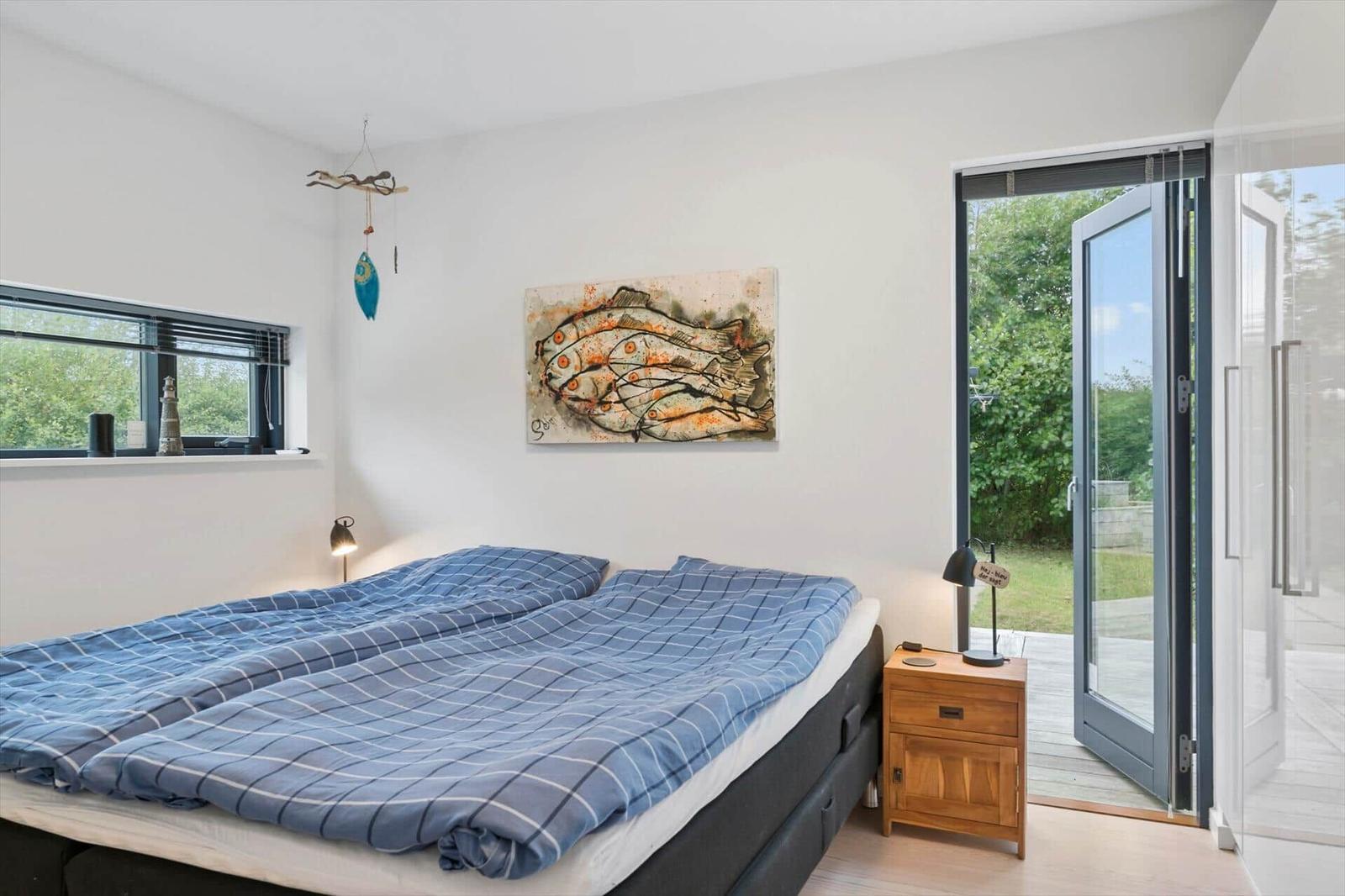 Bedroom with double bed, checked duvets, fish painting and terrace door.