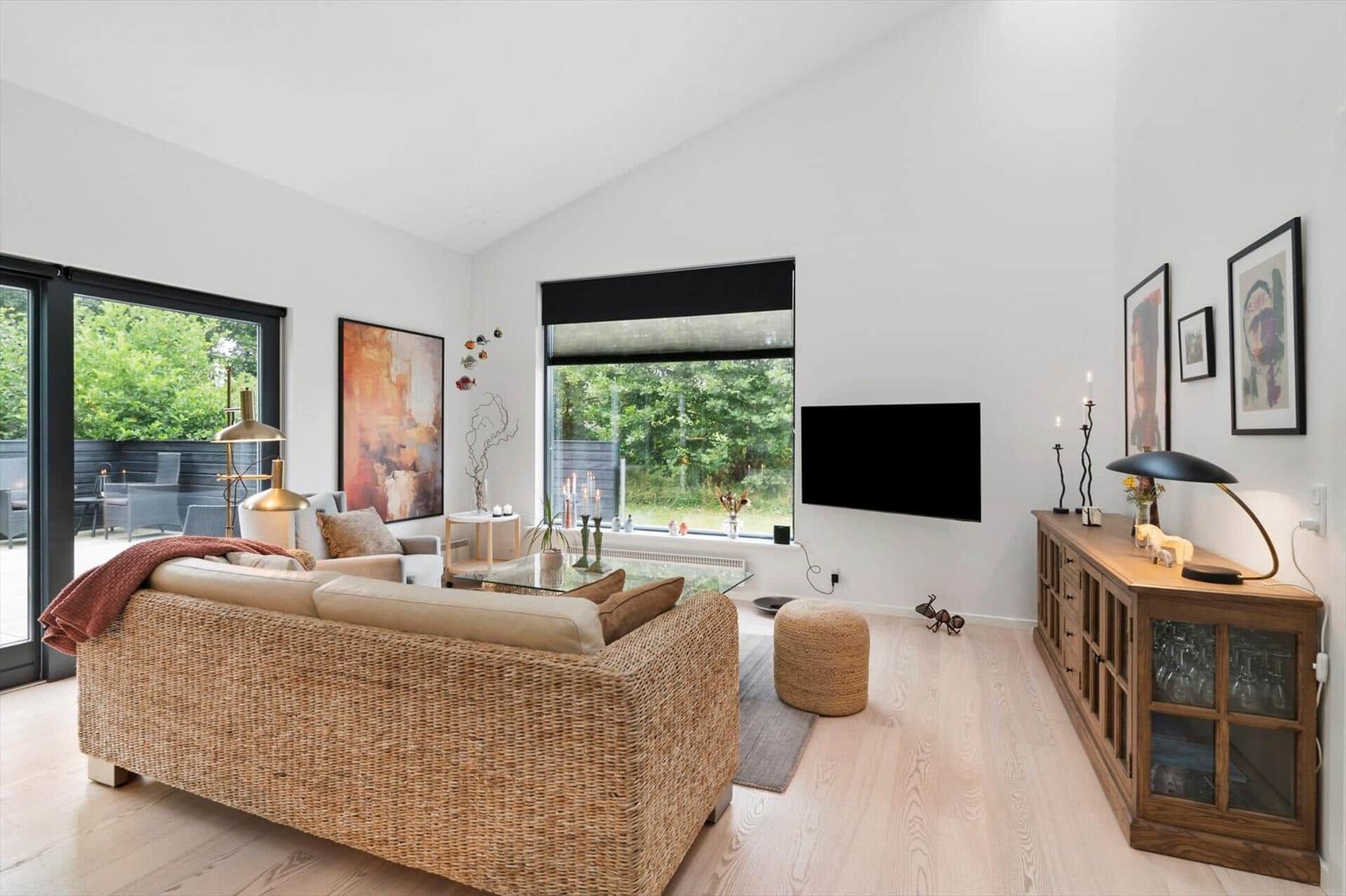 Living room with rattan sofa, coffee table, wall TV and a wooden sideboard.