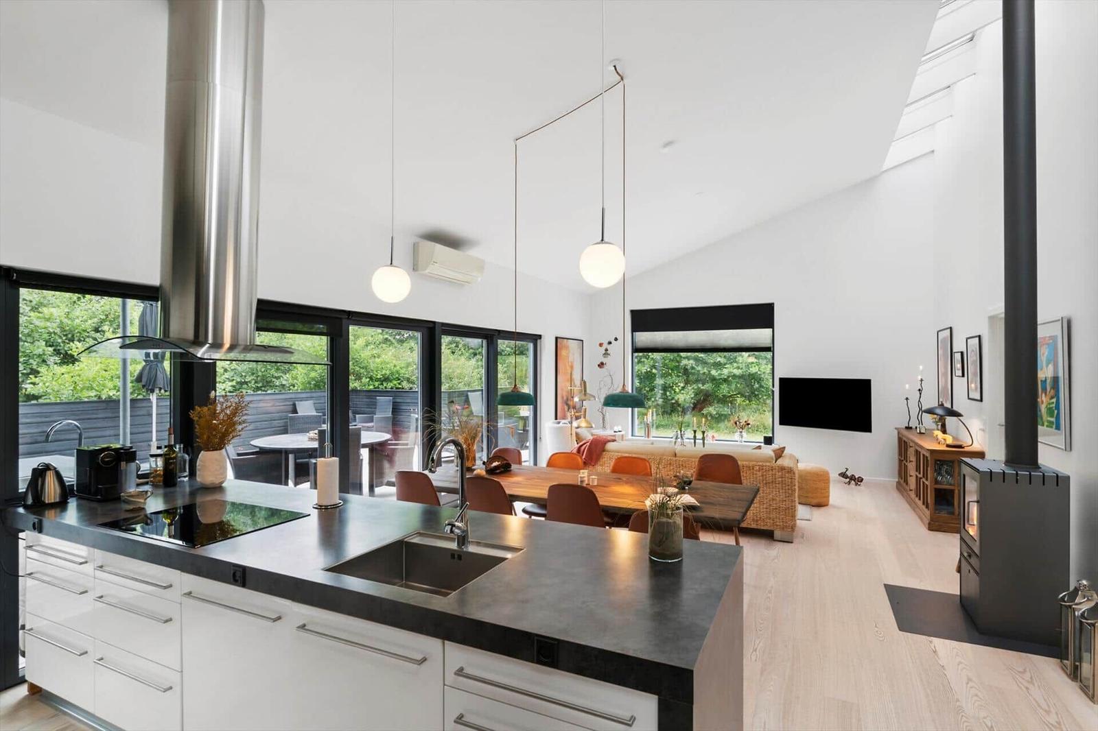 Open living space with kitchen island, dining table, sofa and large glass doors.