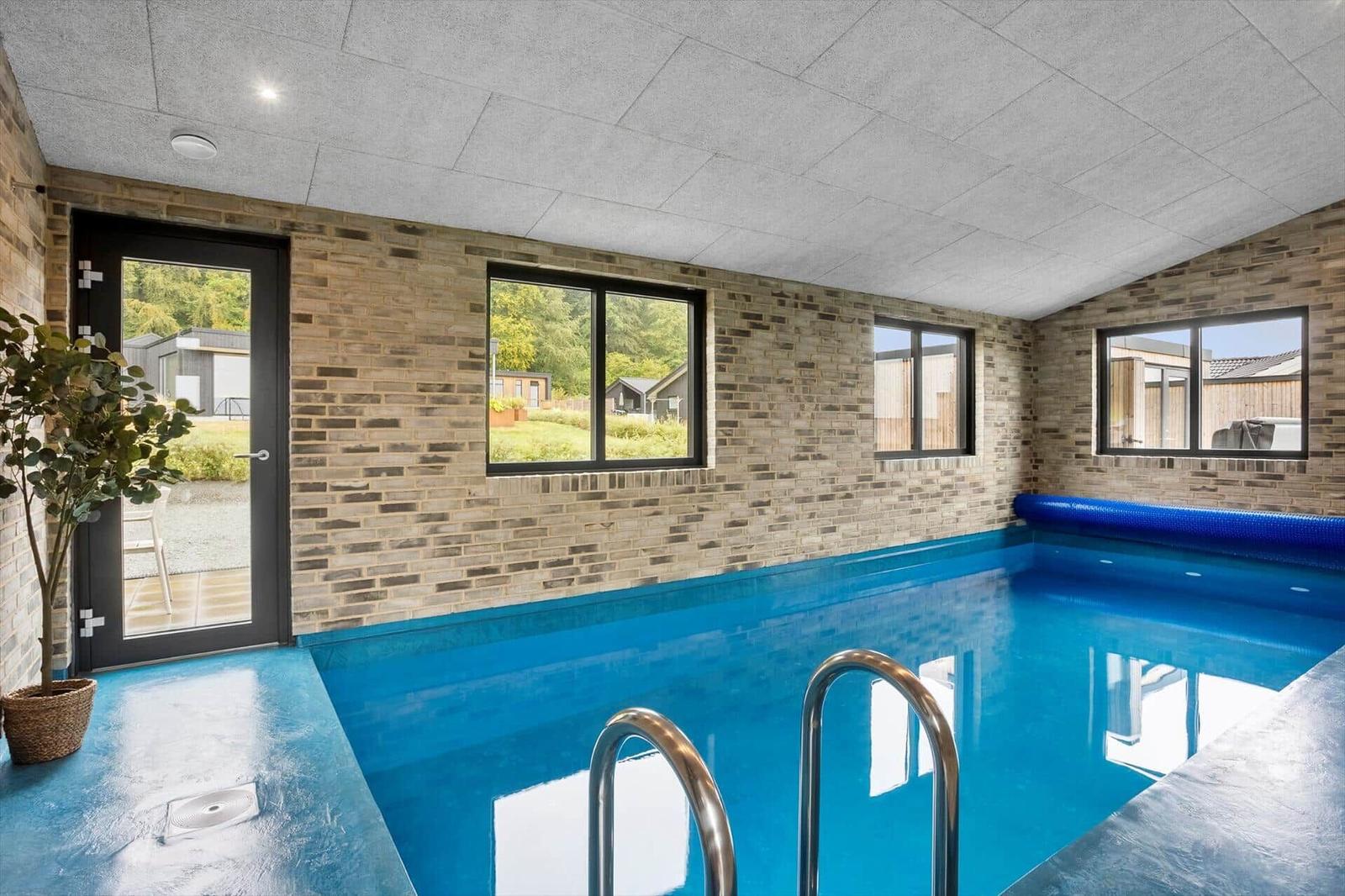 Indoor pool with blue basin, brick walls and glass front.
