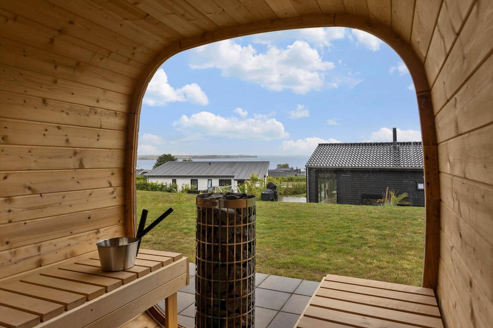 Barrel sauna with heater and wooden benches, view through round window.