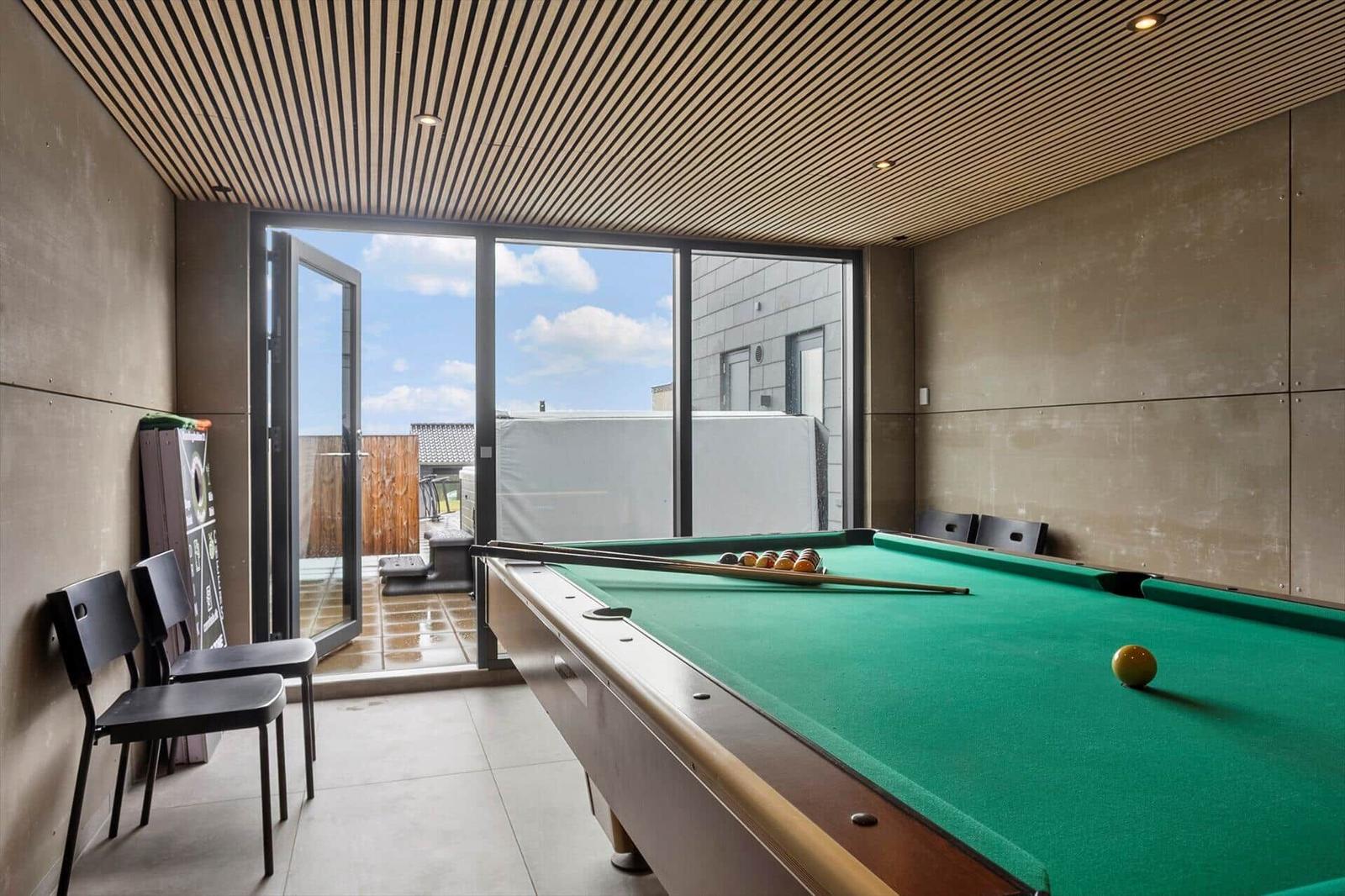 Pool room with green table, grey panel walls and terrace door.