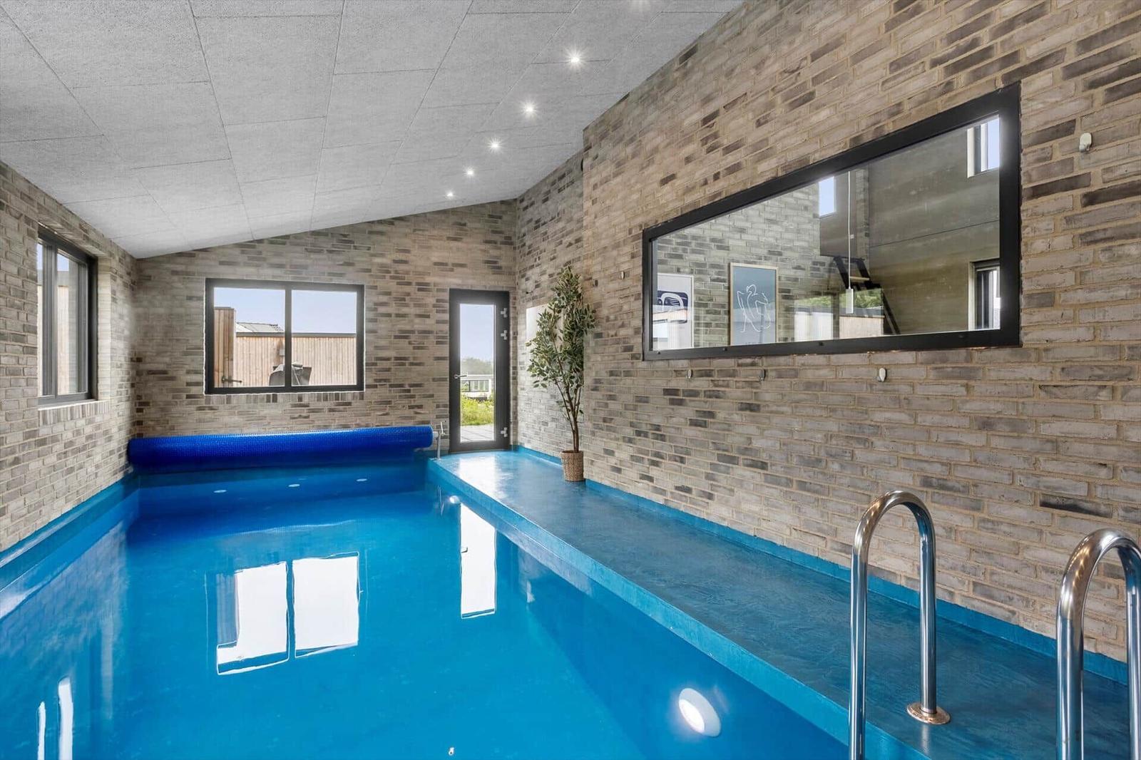 Indoor pool with blue basin, brick walls and interior window.