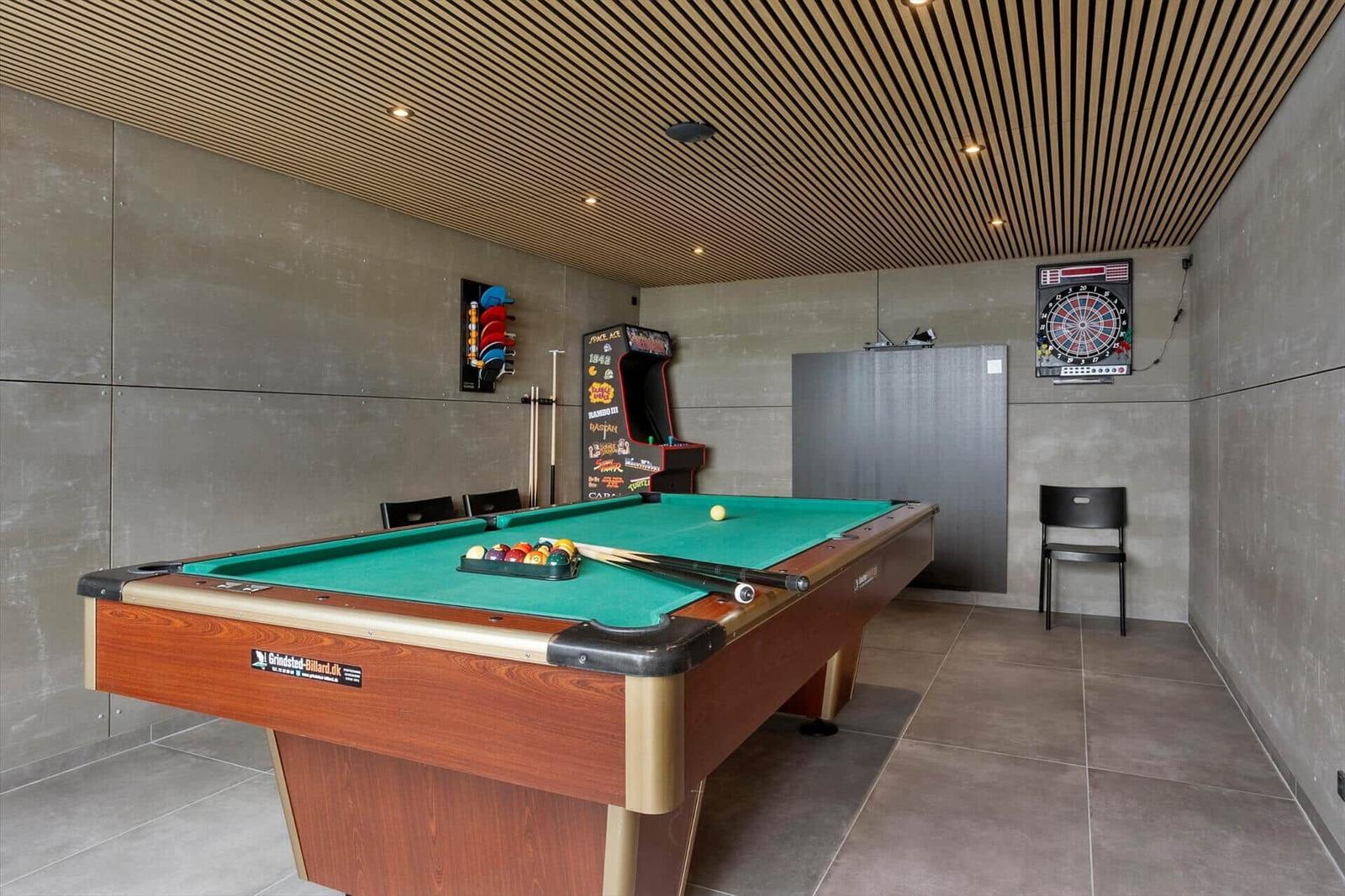 Games room with pool table, arcade cabinet and dartboard.
