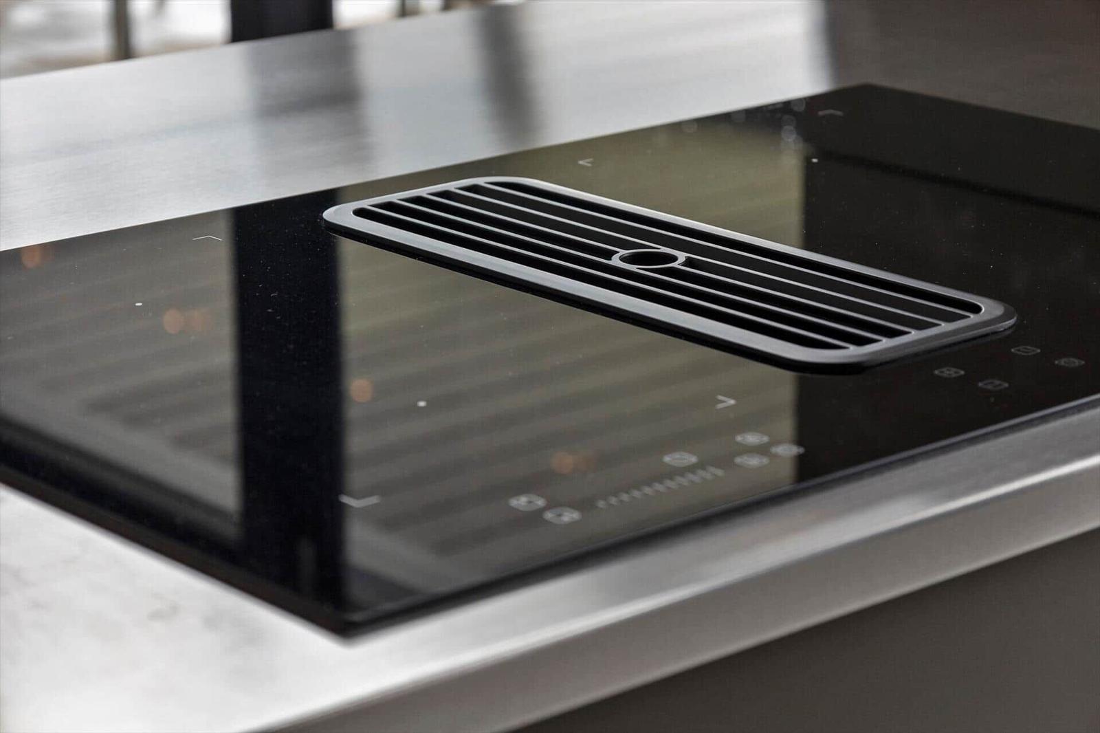Black induction hob with built-in downdraft extractor.