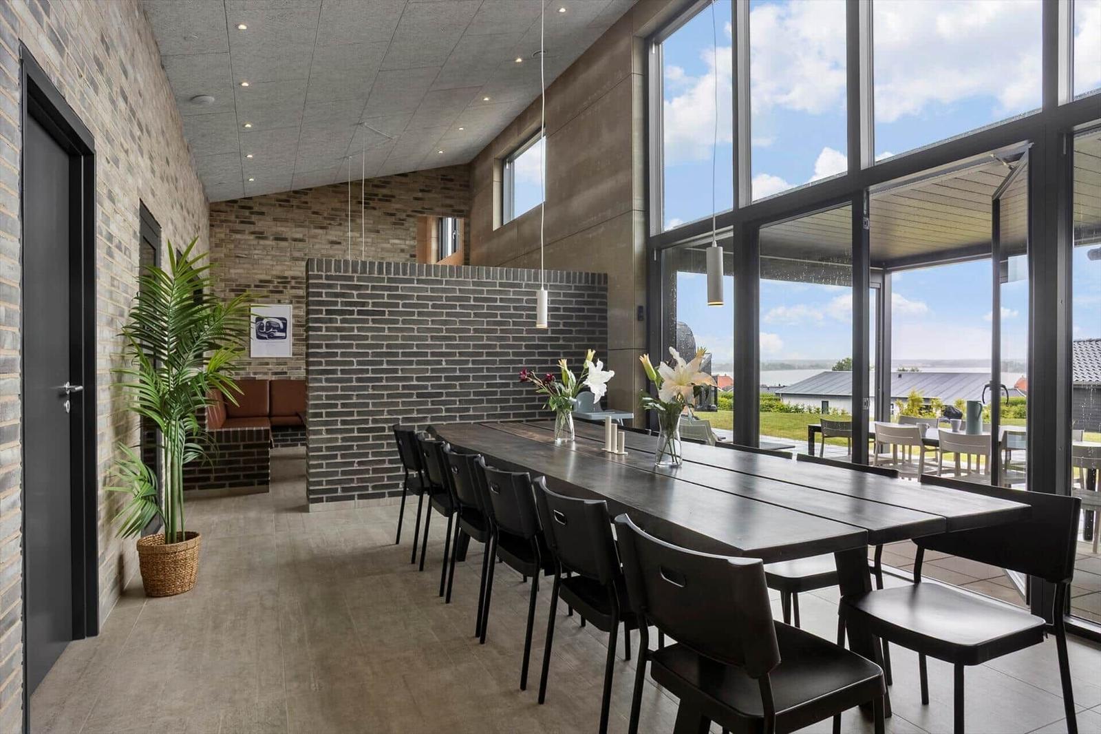Long dining table with black chairs by glass front with wide view.