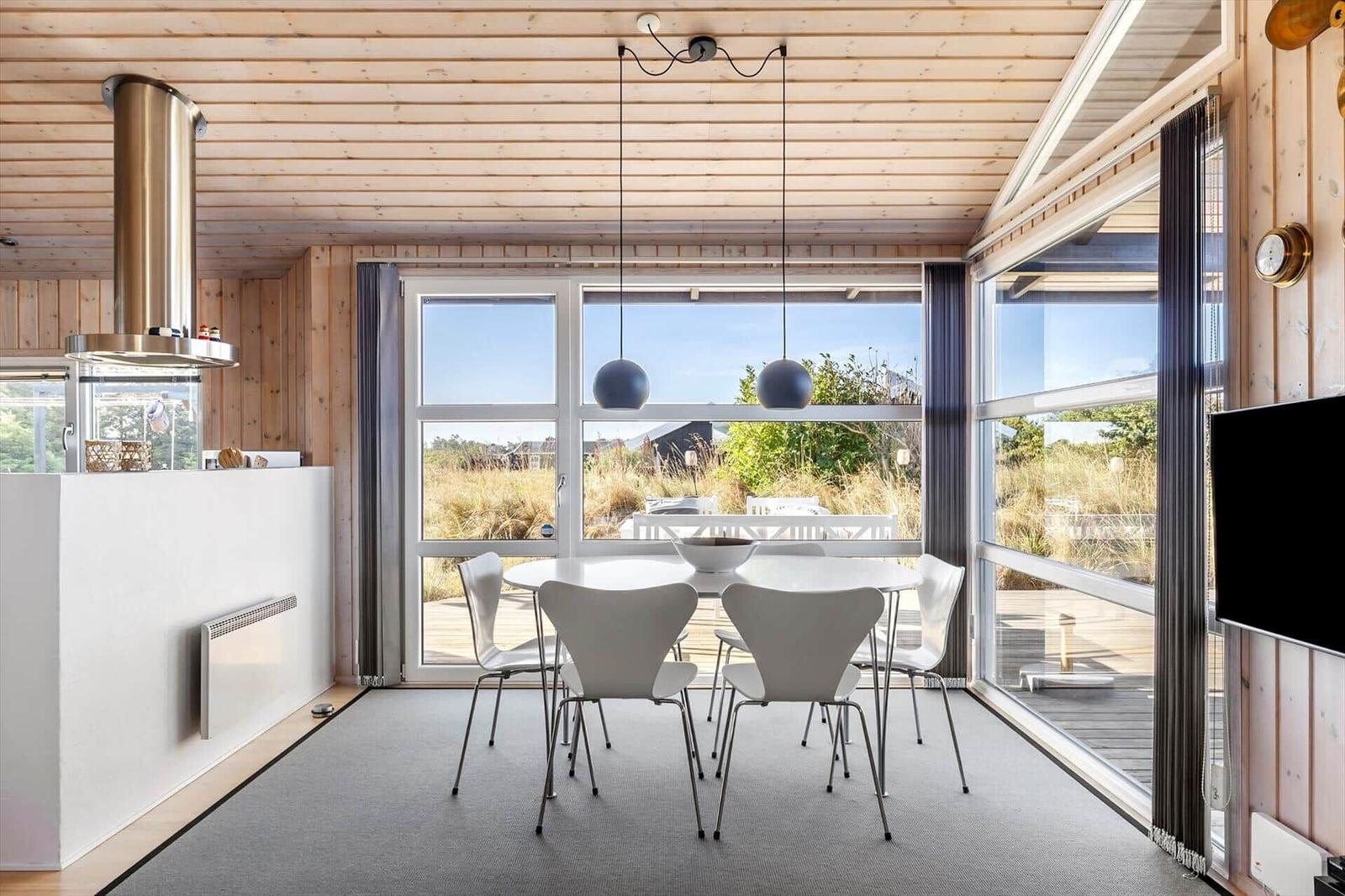 Dining area with round white table, white chairs and large windows to the terrace.