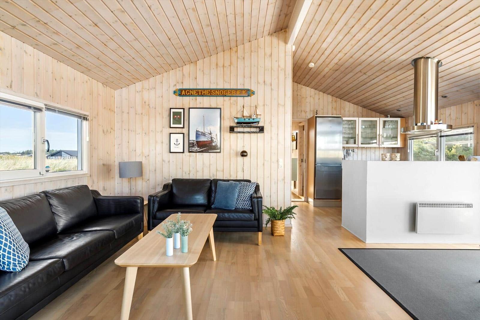 Living kitchen with leather sofas, coffee table and a stainless steel fridge.