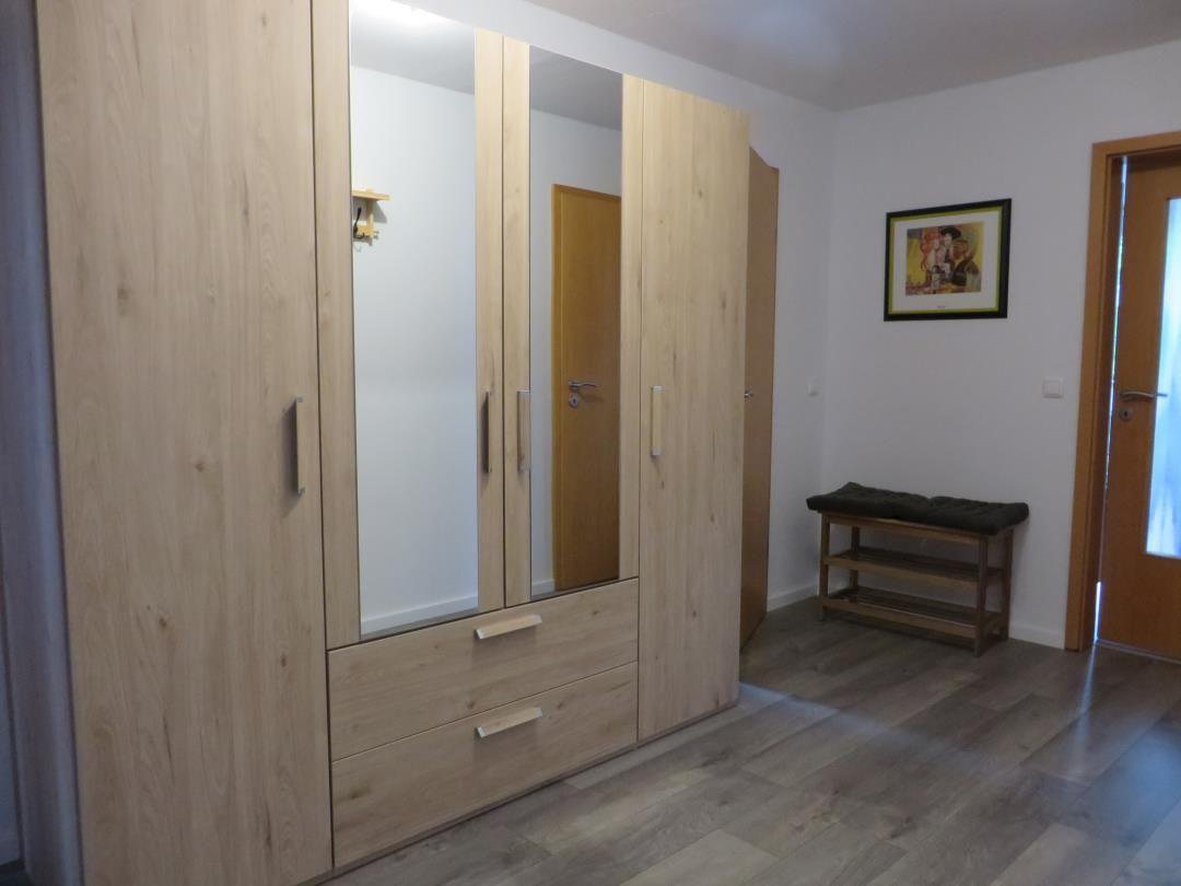 Großer Kleiderschrank in Holzoptik mit Spiegeltüren und Schubladen im Flur.