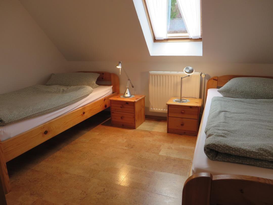 Zwei Einzelbetten mit Nachttischen und Lampen unter Dachfenster.