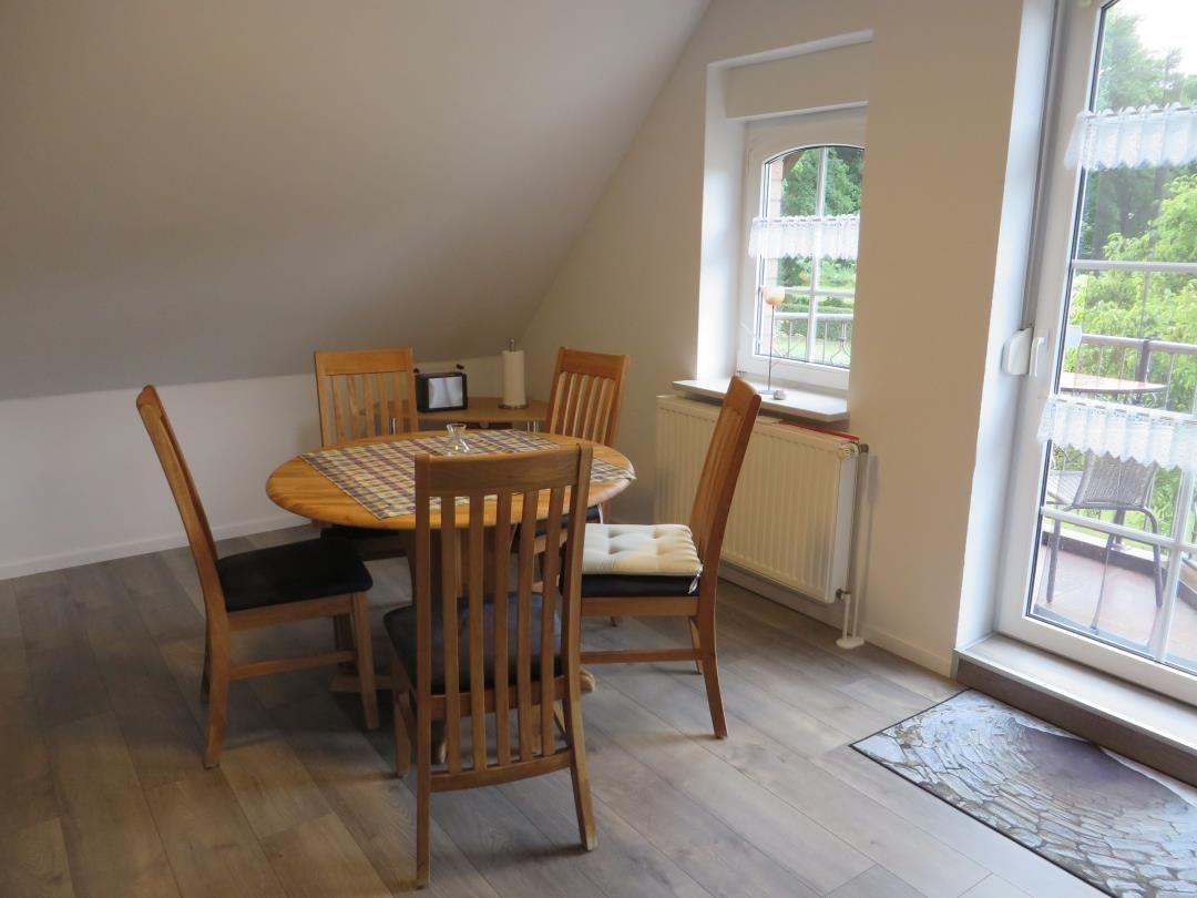 Runder Esstisch mit Holzstühlen neben Balkontür, Fenster und Dachschräge.