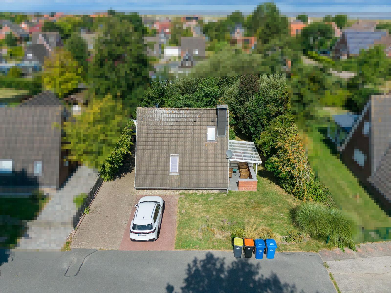 Luftbild vom Haus mit grauem Satteldach, überdachter Terrasse und weißem Auto.