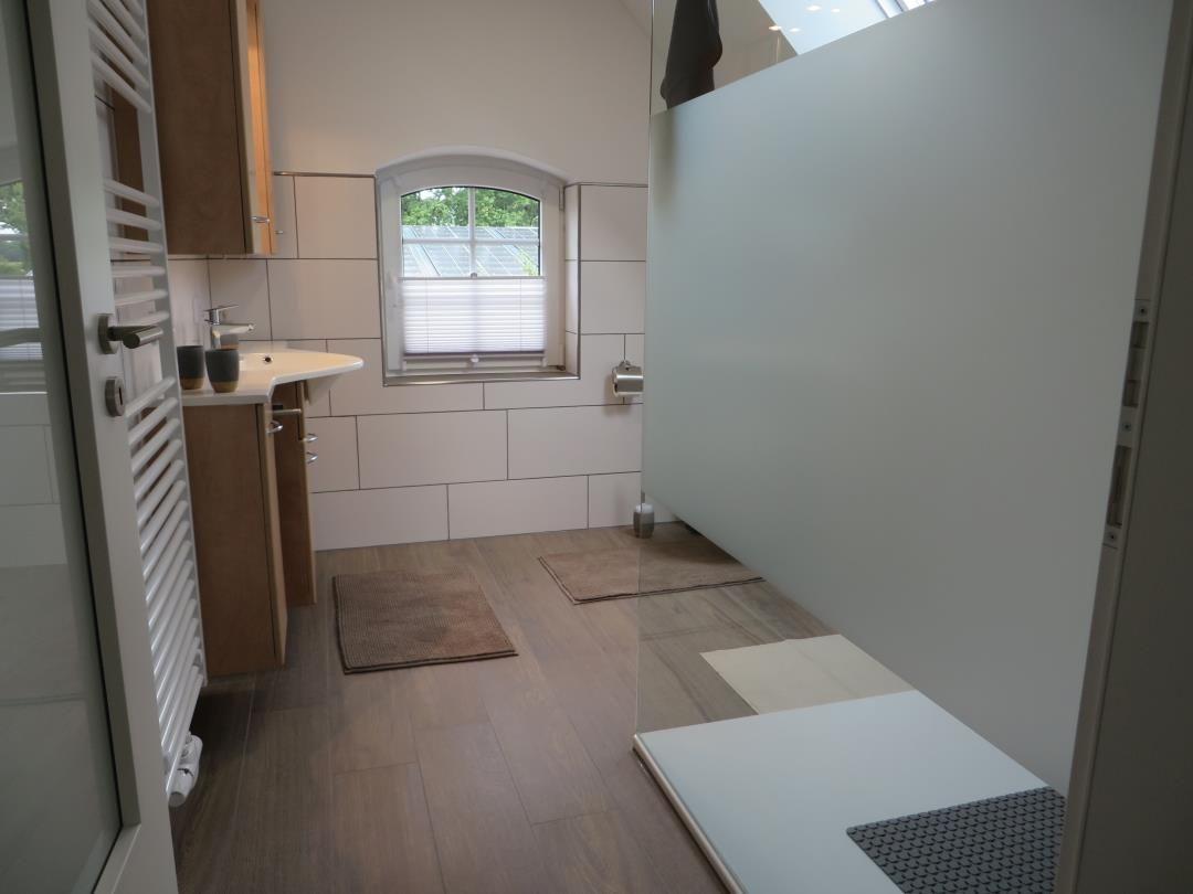 Badezimmer mit Waschtisch, Handtuchheizung, Dusche und Bogenfenster.