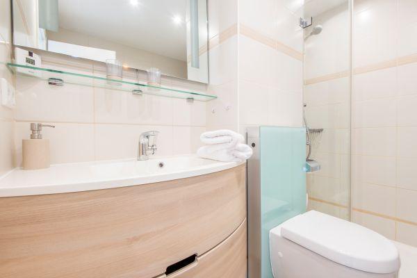 Badezimmer mit Holzwaschtisch, Handtüchern, WC und Glasdusche.
