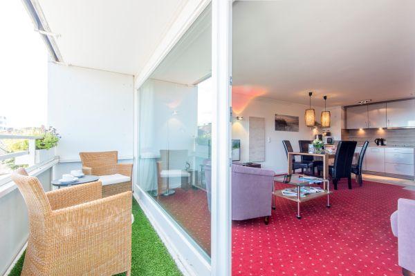 Balkon mit Korbsesseln, Kunstrasen und Blick in den Wohnraum.