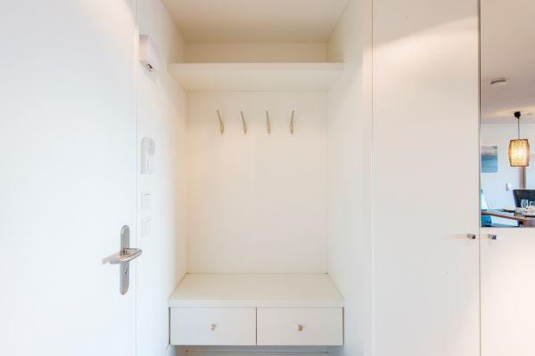 Weiße Garderobe mit Haken, Bank und Schubfächern im Flur