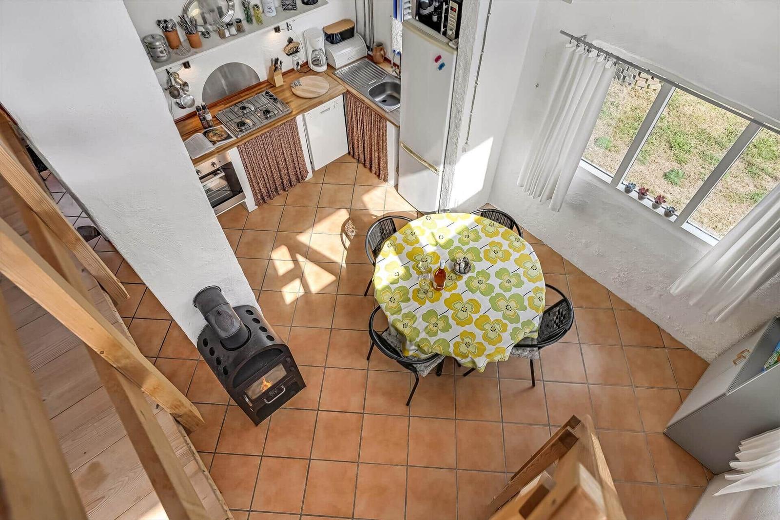 Blick von oben auf Küche mit Gasherd, rundem Esstisch und Kaminofen.