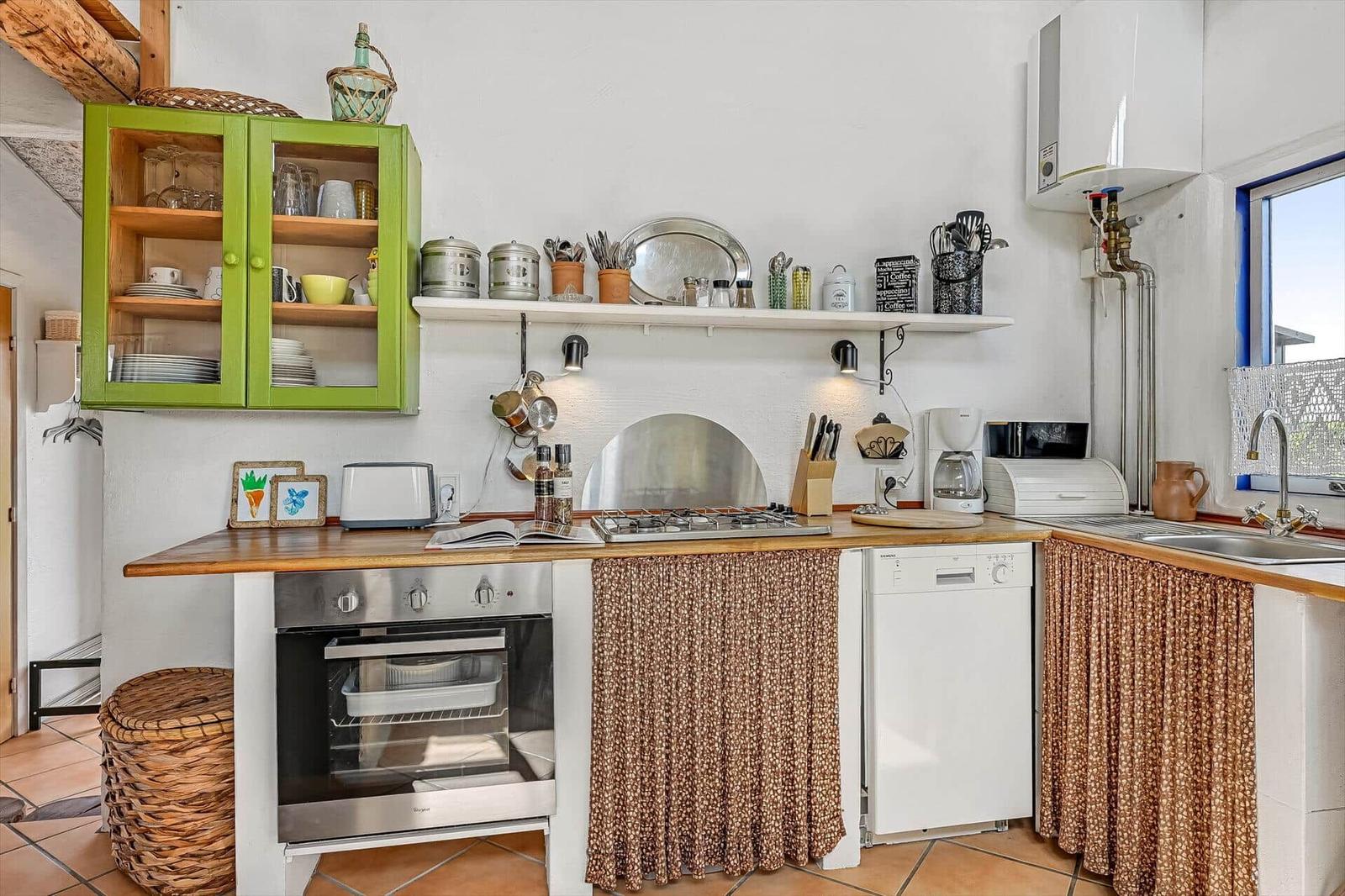 Küchenzeile mit Holzplatte, Backofen, Spülmaschine, grünem Schrank und Spüle.