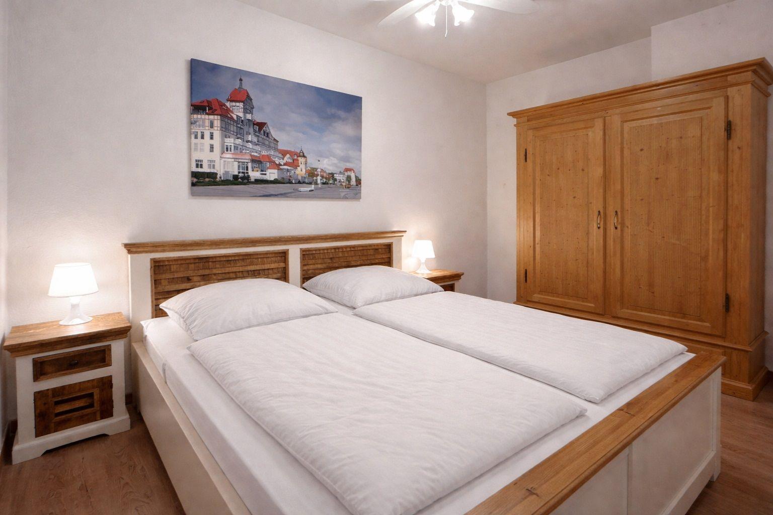 Schlafzimmer mit Doppelbett, Holzschrank und Wandbild.