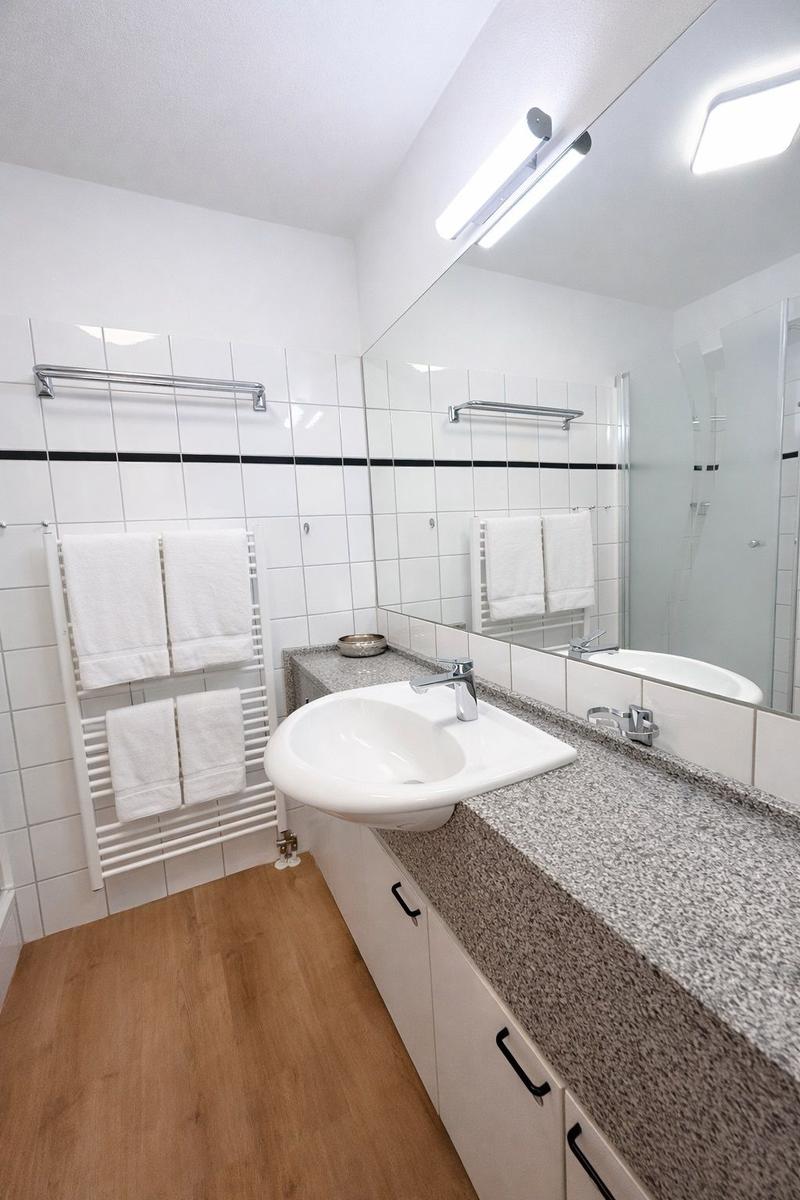 Badezimmer mit Waschbecken, Spiegel, Handtuchhalter und Dusche