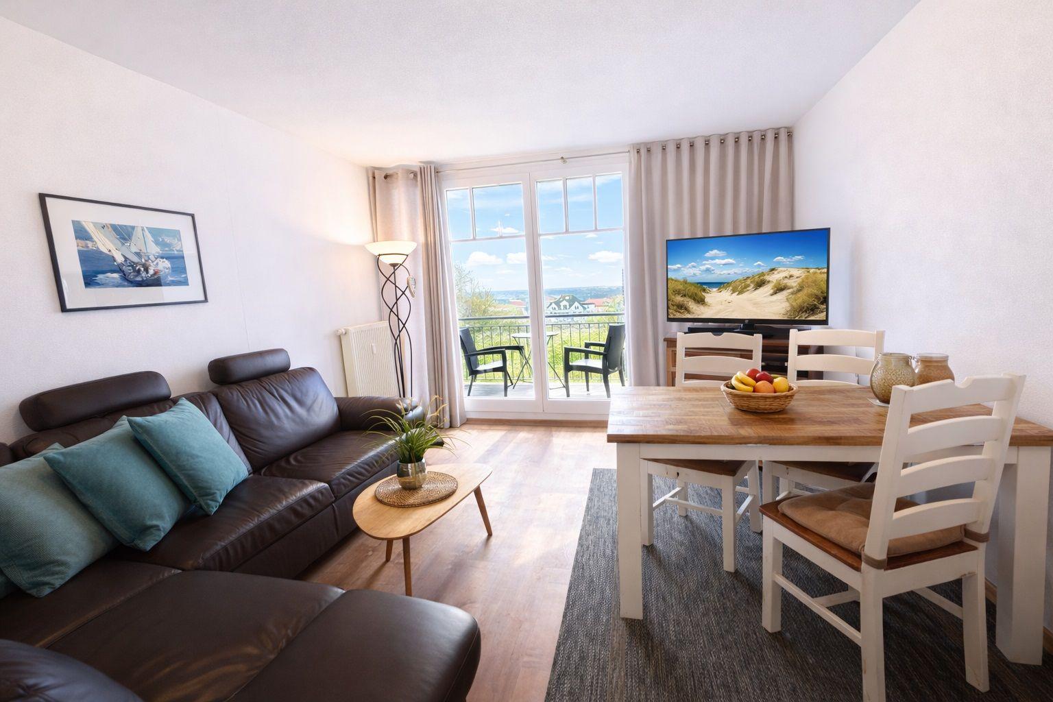 Wohn- und Essbereich mit Sofa, Esstisch und Balkonansicht.