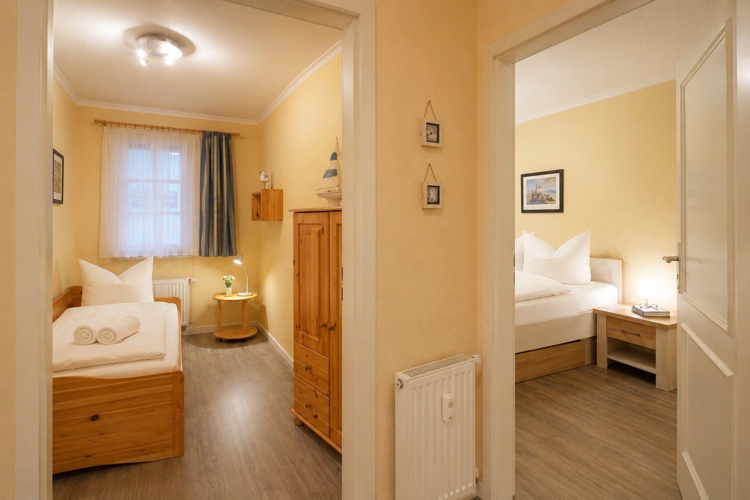 Schlafzimmer mit Bett, Nachttisch und Fenster mit Vorhängen.