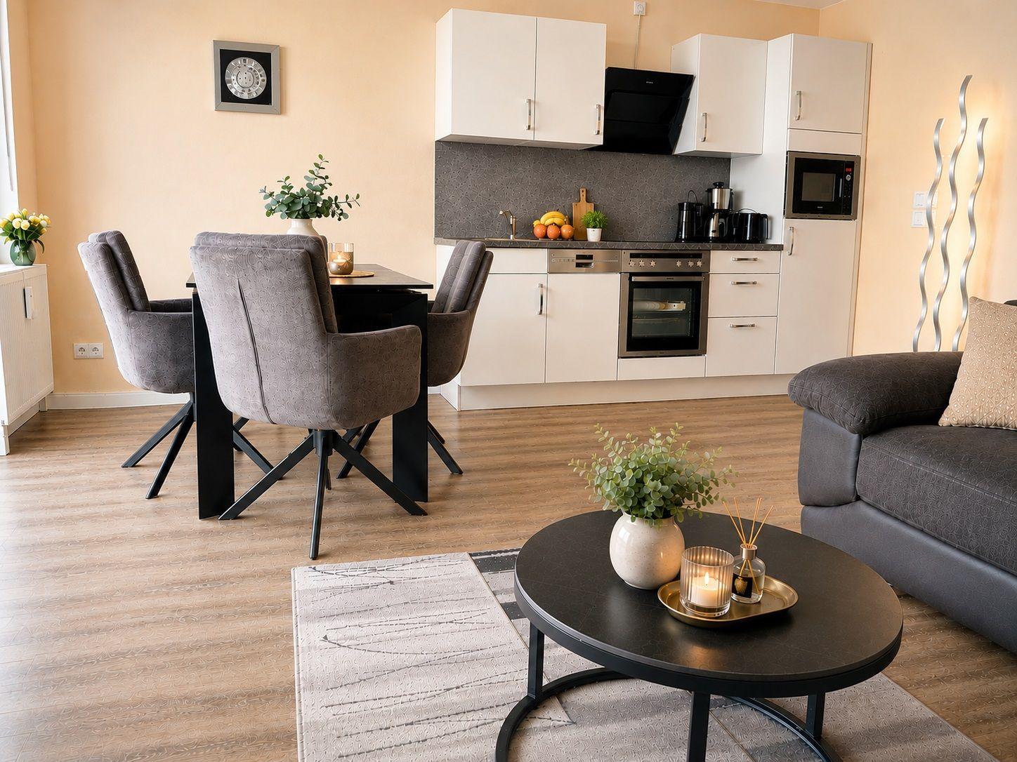 Wohn- und Essbereich mit Küchenzeile, Sofa und Esstisch mit Stühlen.