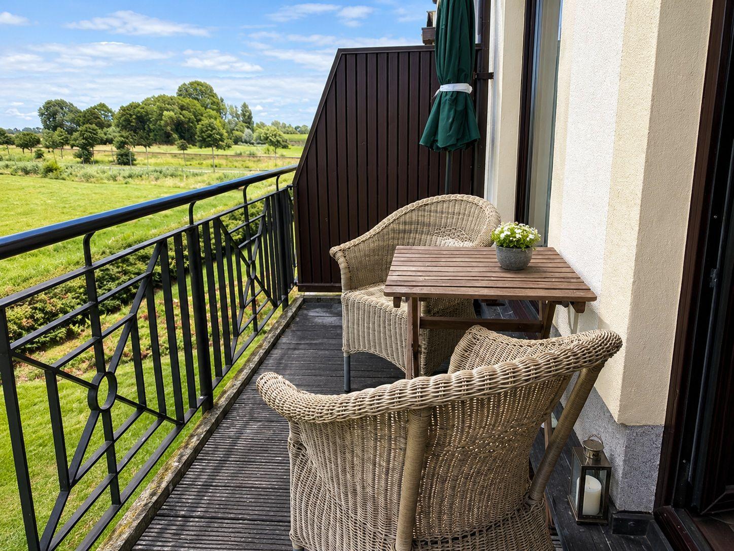 Balkon mit zwei Stühlen und Tisch, Blick auf Schnee und Wasser.