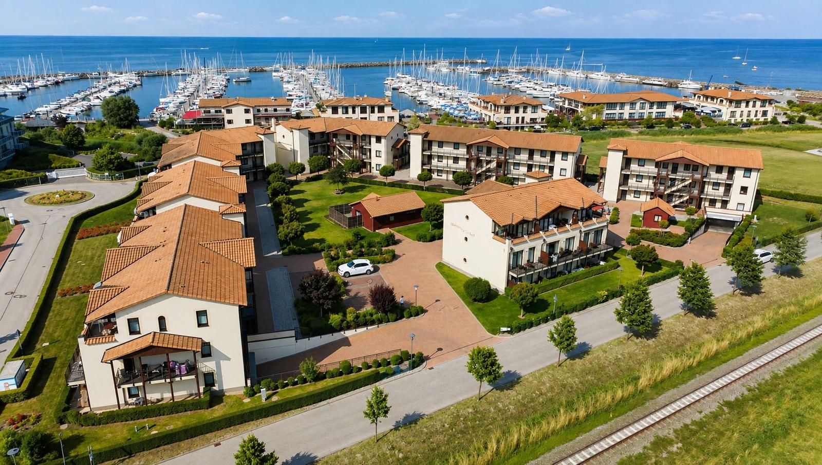 Villa mit Terrasse, umgeben von Grünflächen und direkt am Hafen mit Booten.