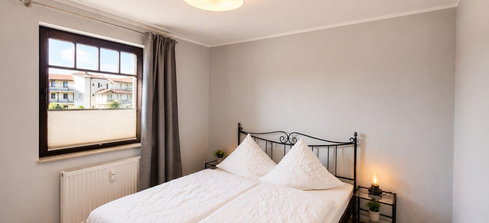 Schlafzimmer mit Bett, Fenster und Lampe.