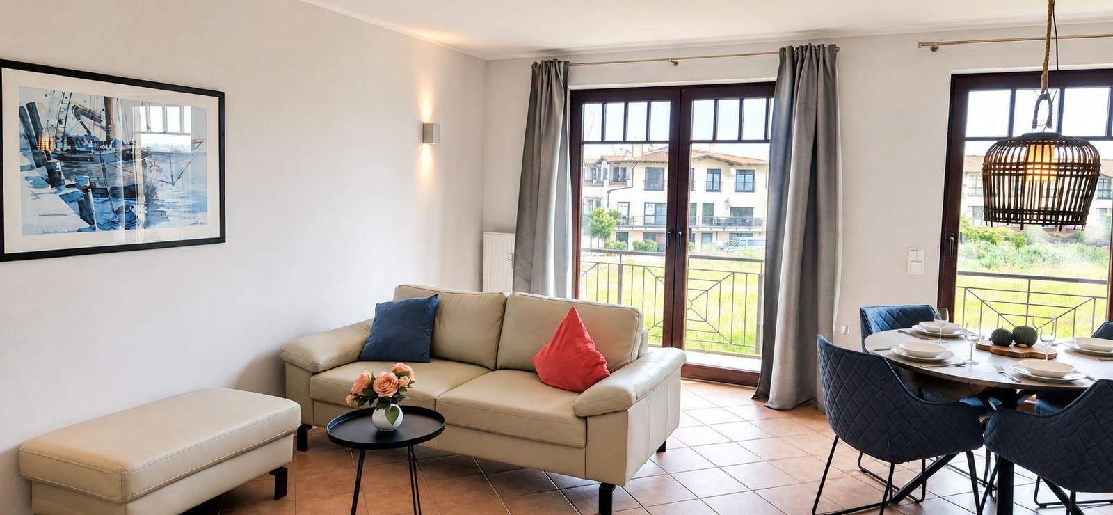 Wohnbereich mit Sofa, Esstisch und Balkonansicht. Wandbild und Beleuchtung sichtbar.