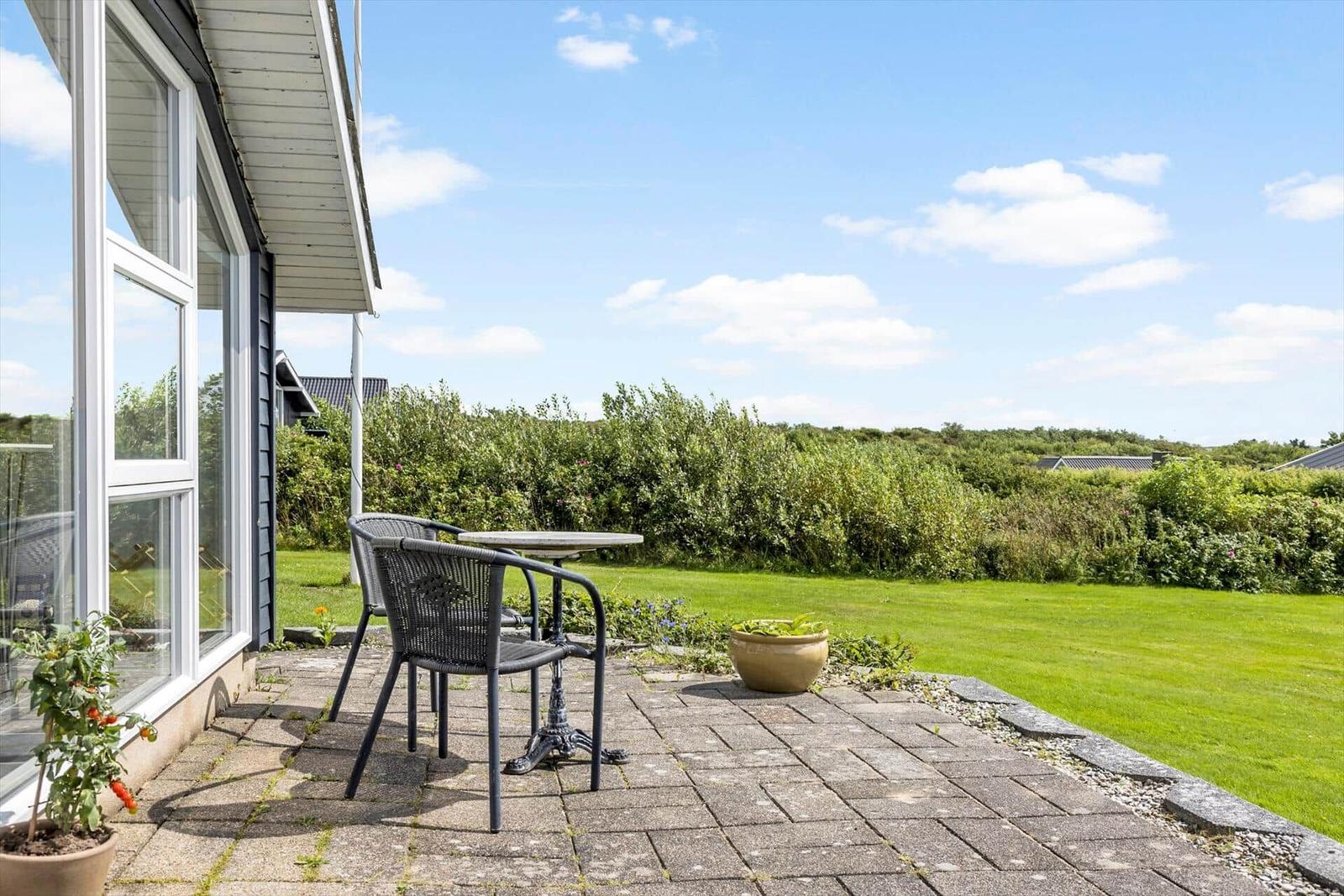 Esszimmer mit Holztisch, schwarzen Stühlen und gelben Wänden. Durchgang zu Terrasse und Wohnbereich.