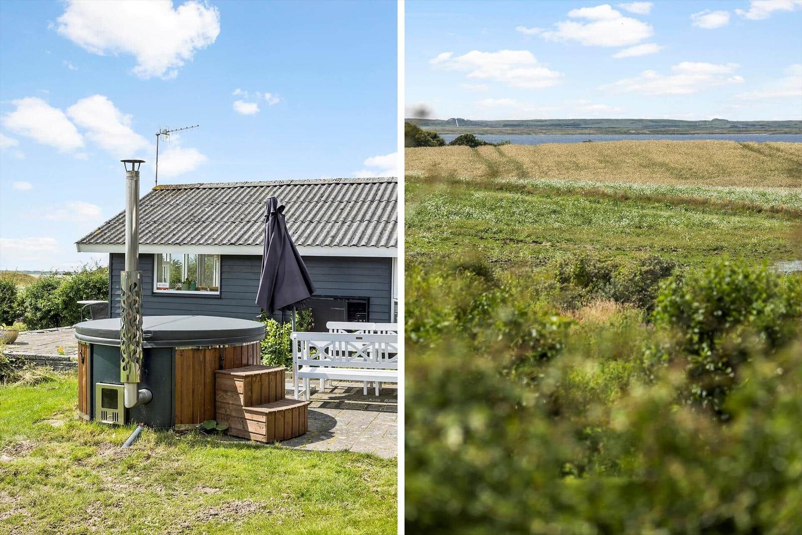 Terrasse mit Tisch und Stühlen, Blick auf grünen Rasen und Hecke.