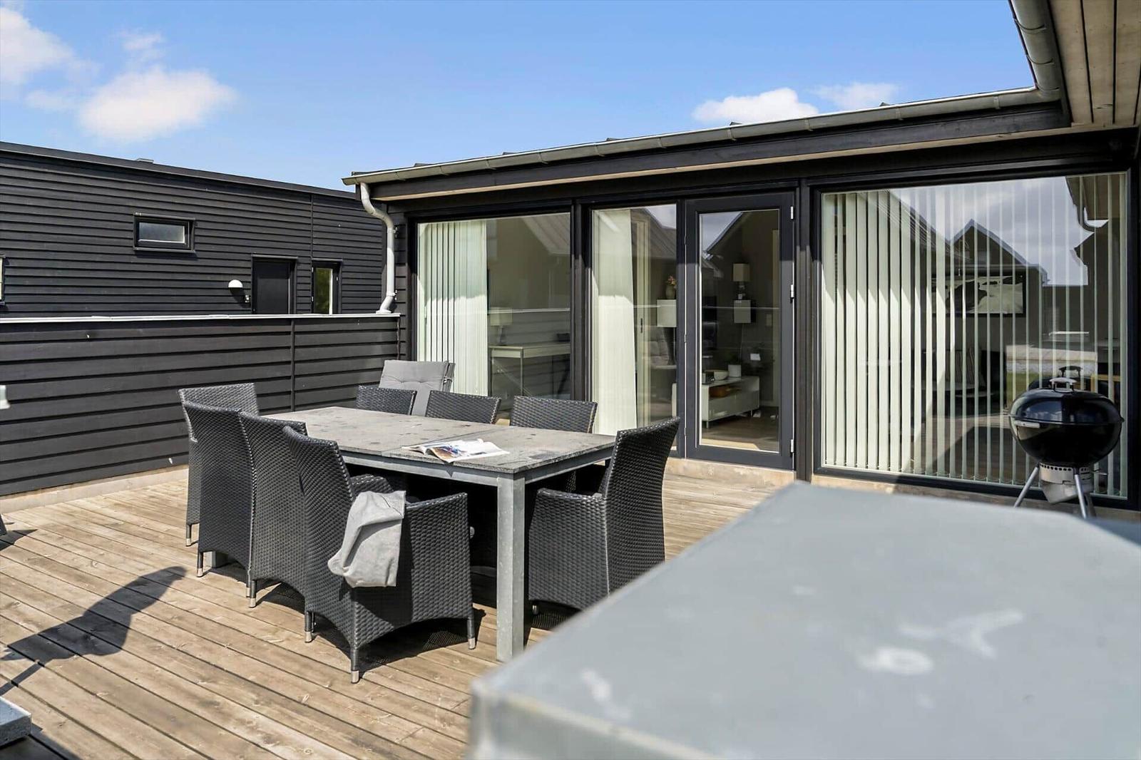 Moderne Ferienwohnung mit dunkler Holzfassade und Gartenbereich.