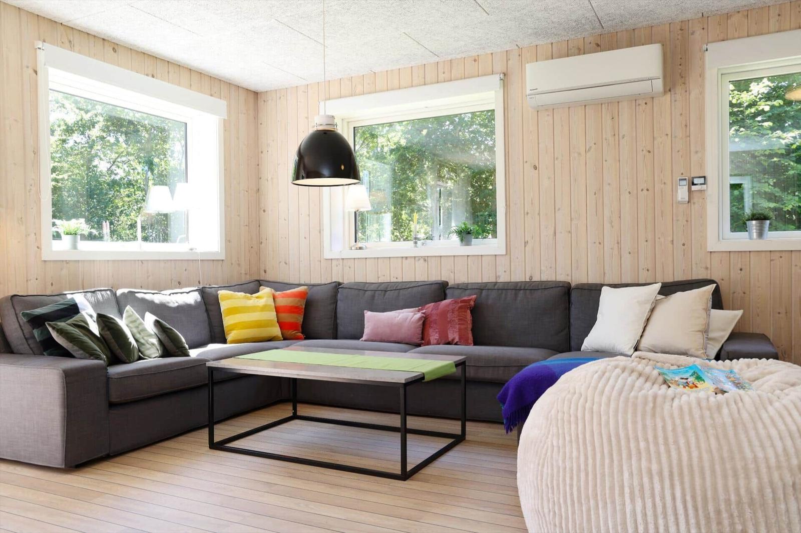 Schlafzimmer mit Holzwand, Bett und Fenster mit Blick auf Grün.