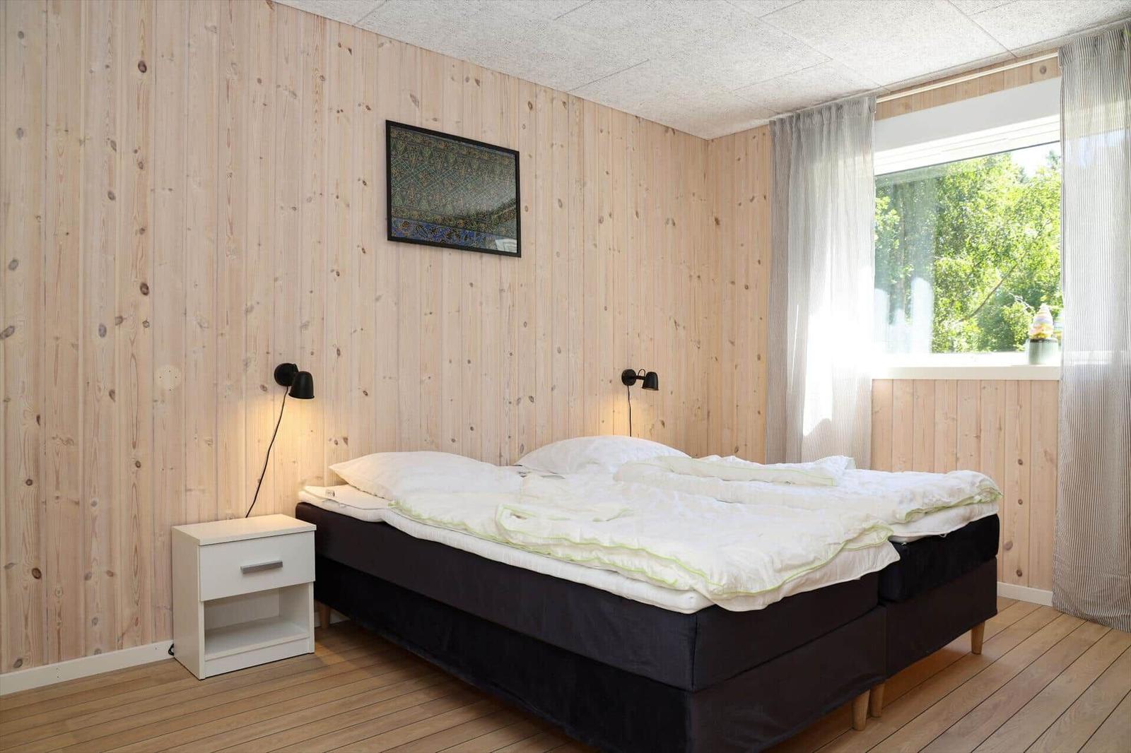 Holztisch mit Stühlen und Getränken vor Holzstapel und Bäumen.